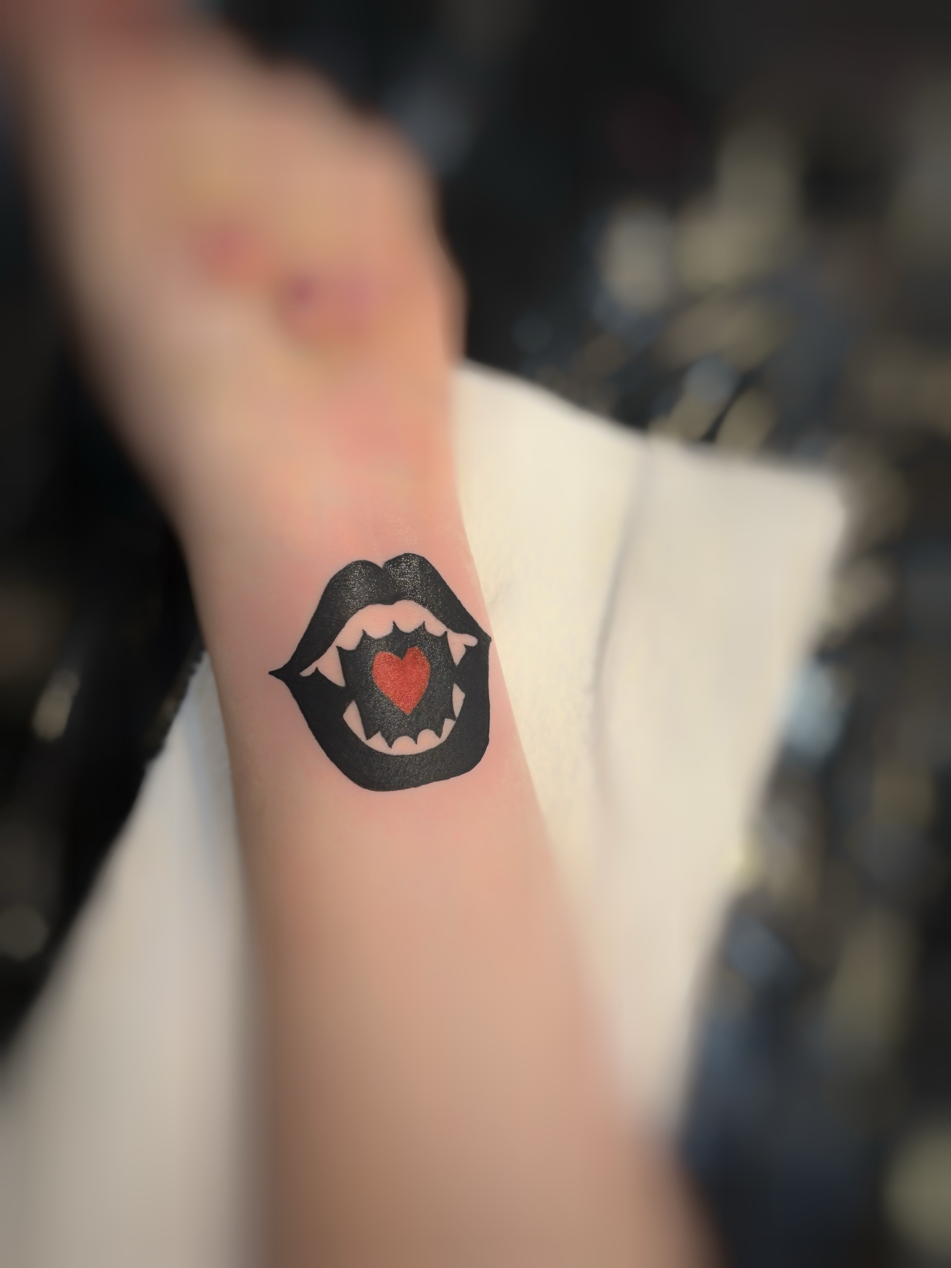 Lips with heart black and grey tattoo on the forearm by Holly