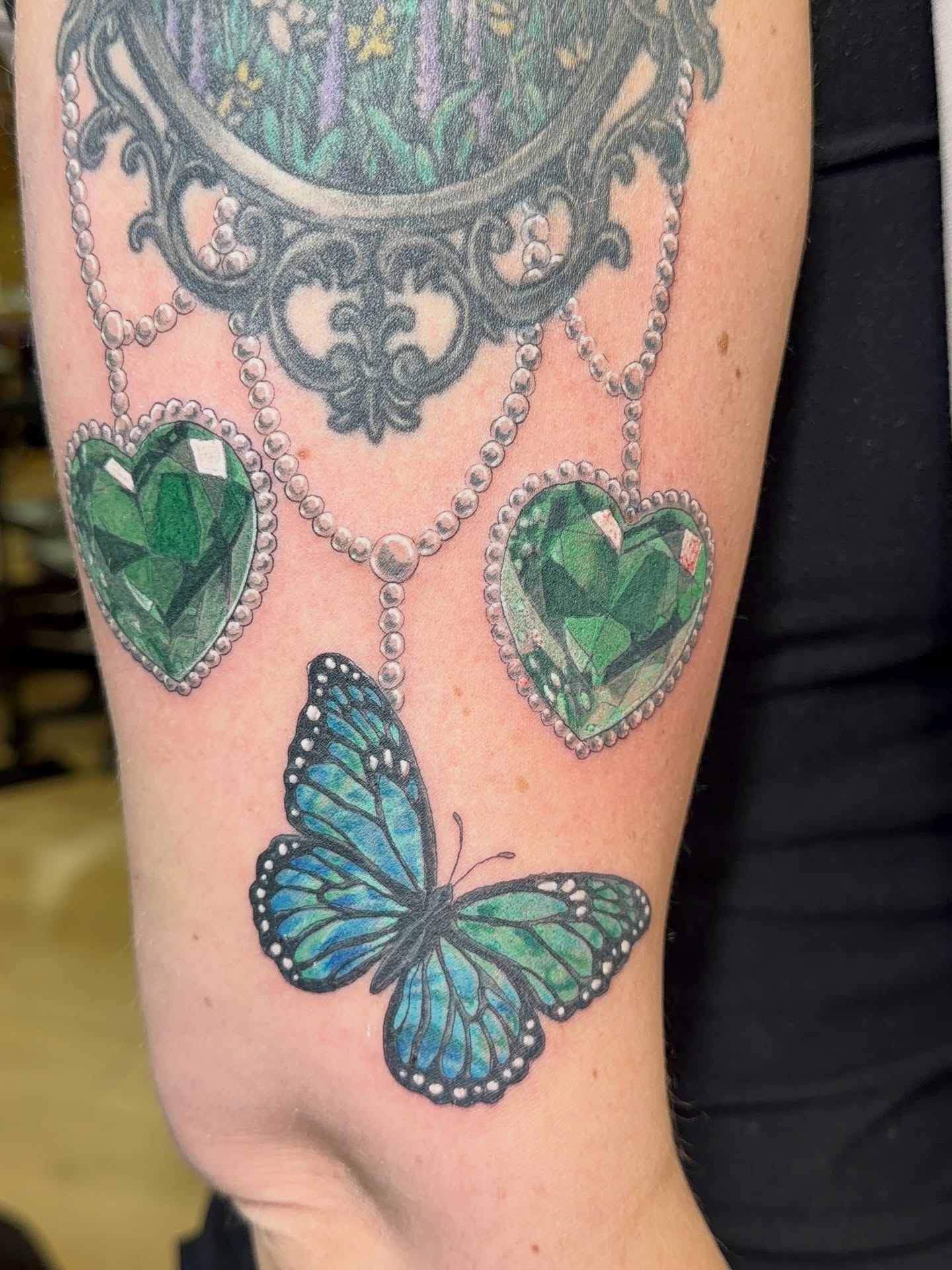 Butterfly and gemstone hearts realism tattoo on the forearm by Dani Fried Tattoos