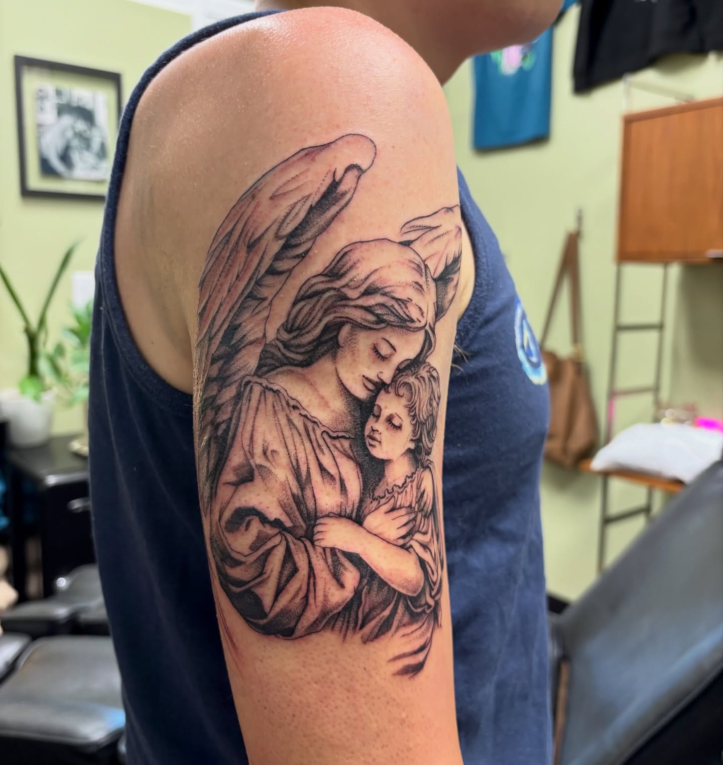 Angel and child realism tattoo on the upper arm by sydney honn
