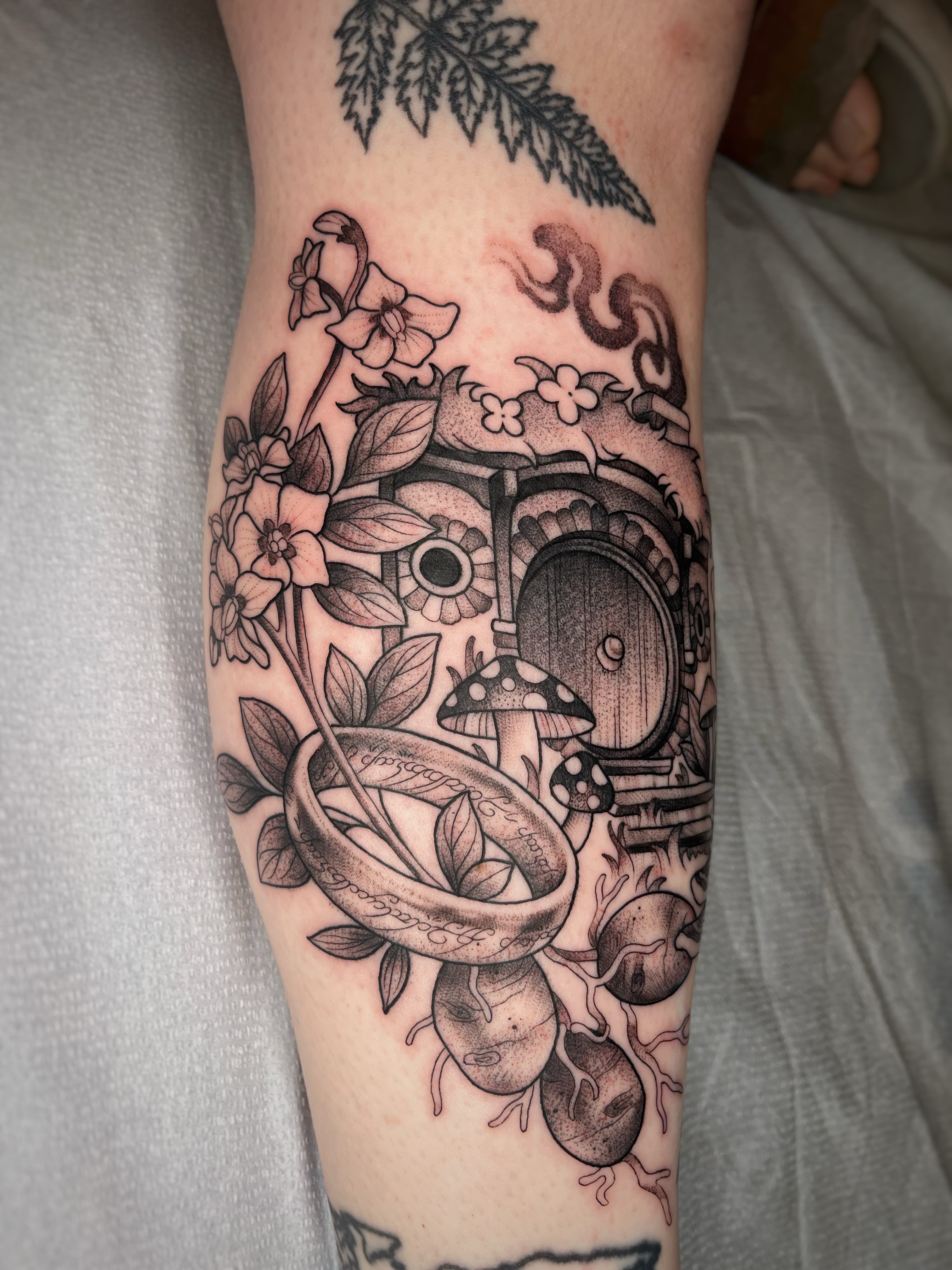 Camera and flora realism tattoo on the forearm by Emi Collison