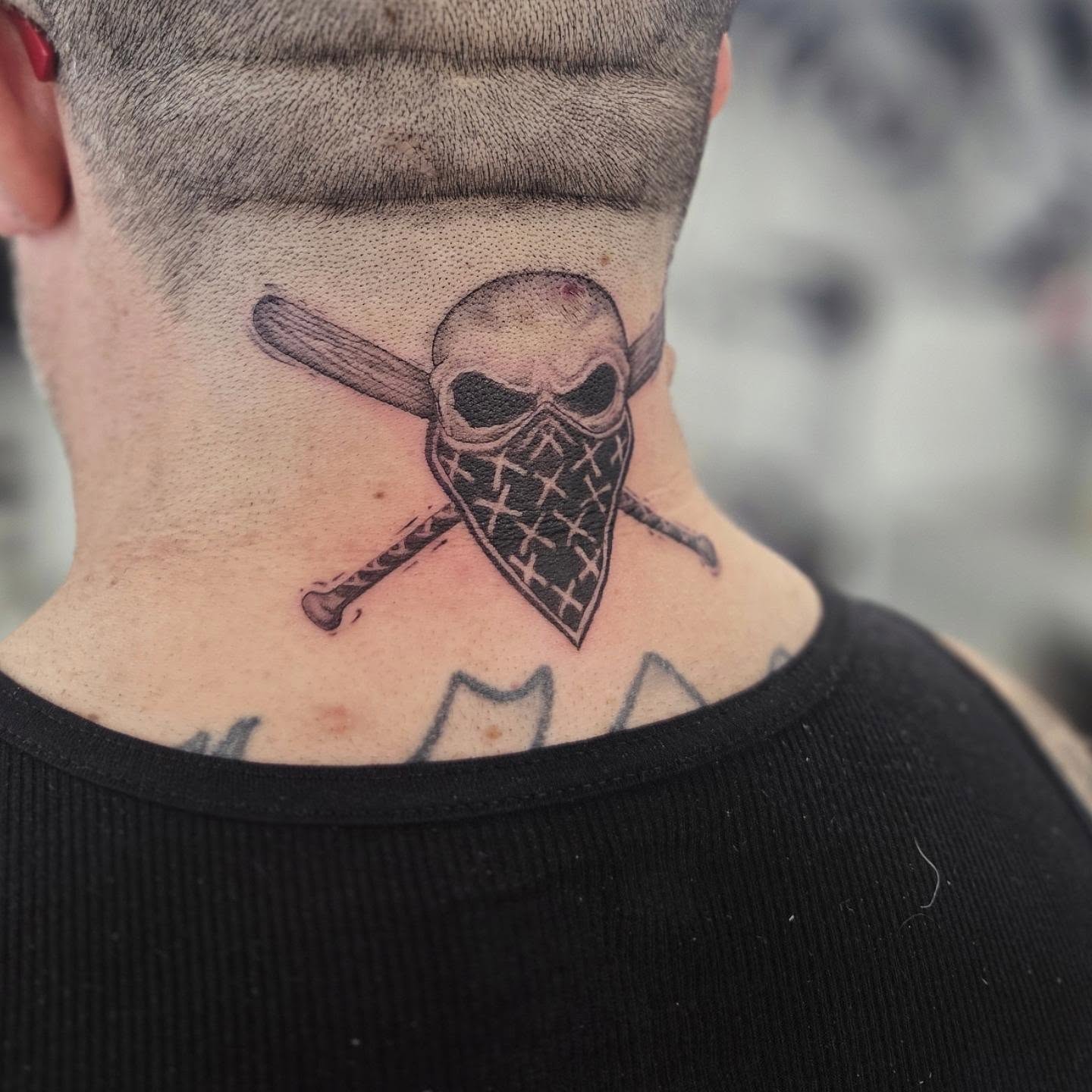 Skull with bandana and crossed bats black and grey tattoo on the neck by Molly DeSmedt