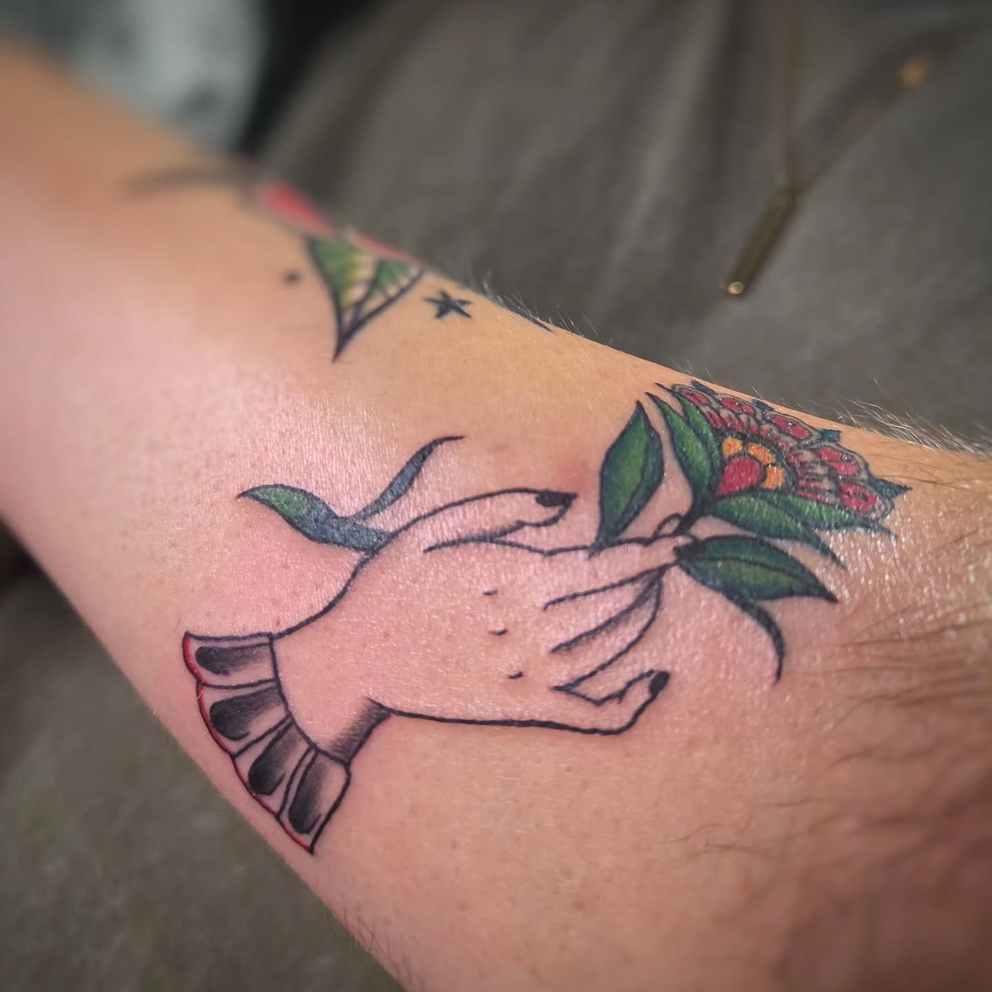 Hand holding flower American traditional tattoo on the forearm by Jam ⚡️🐉🖤