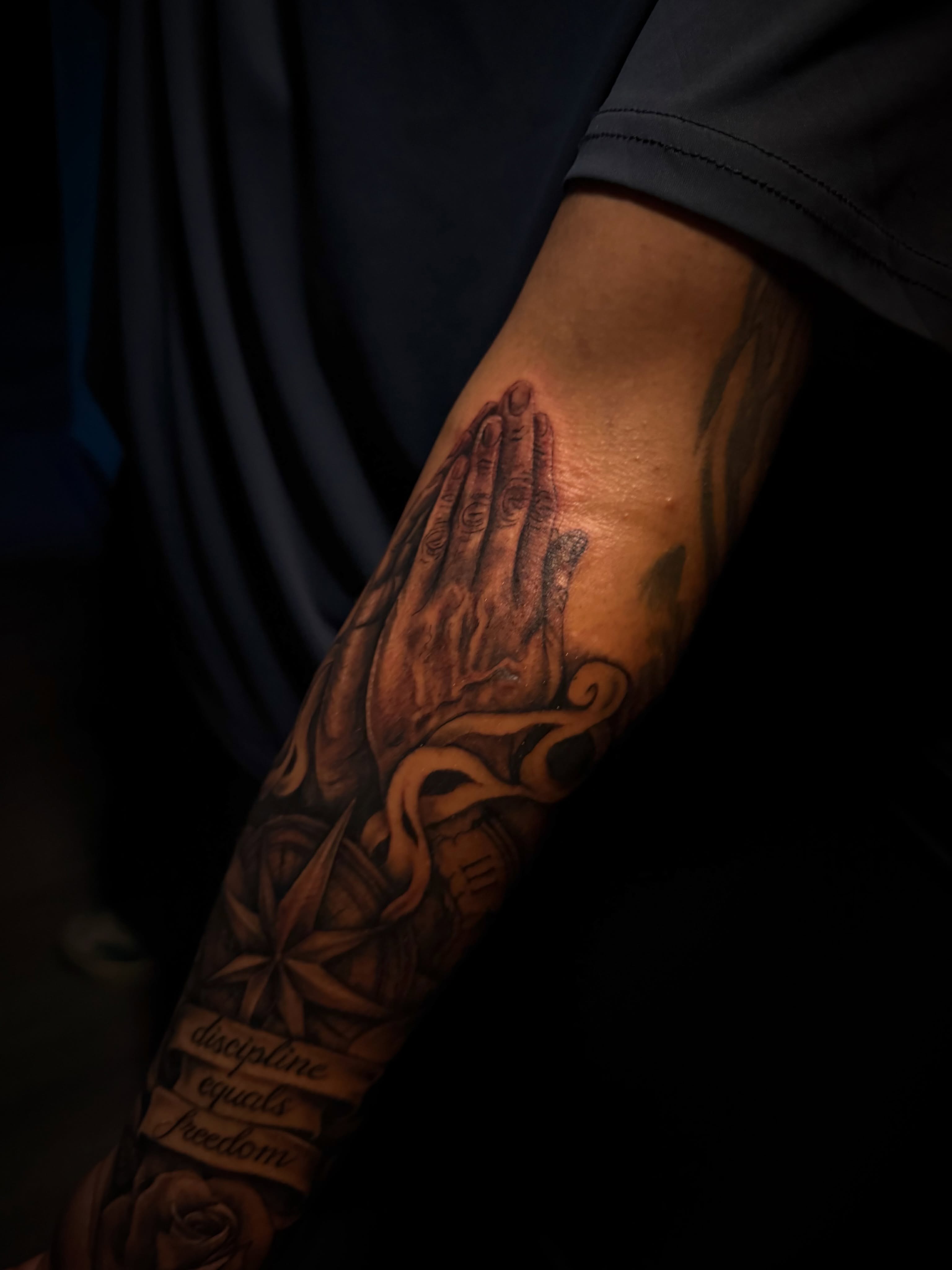 Praying hands realism tattoo on the forearm by Christa Martinez