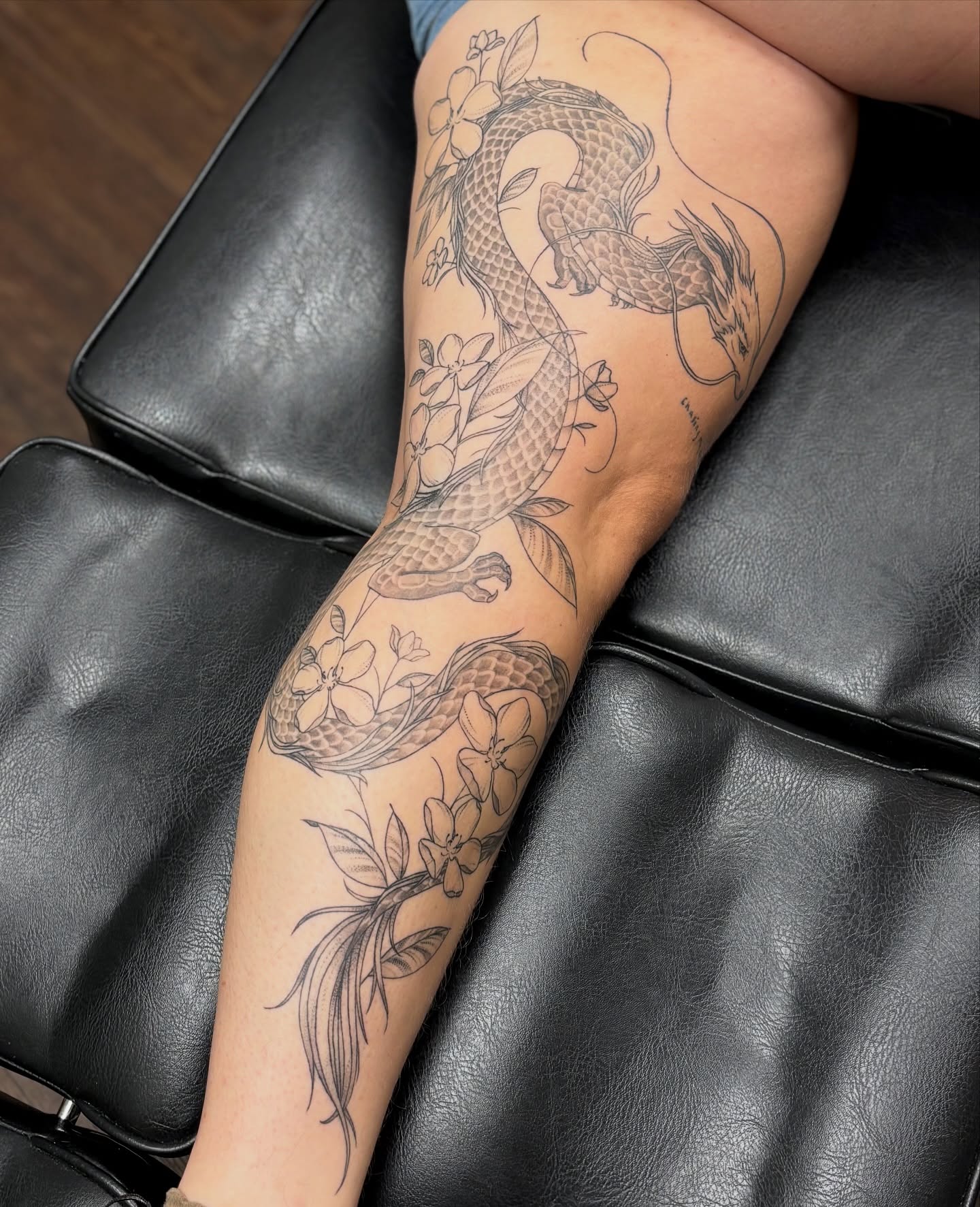 Dragon and flowers black and grey tattoo on the forearm by sydney honn