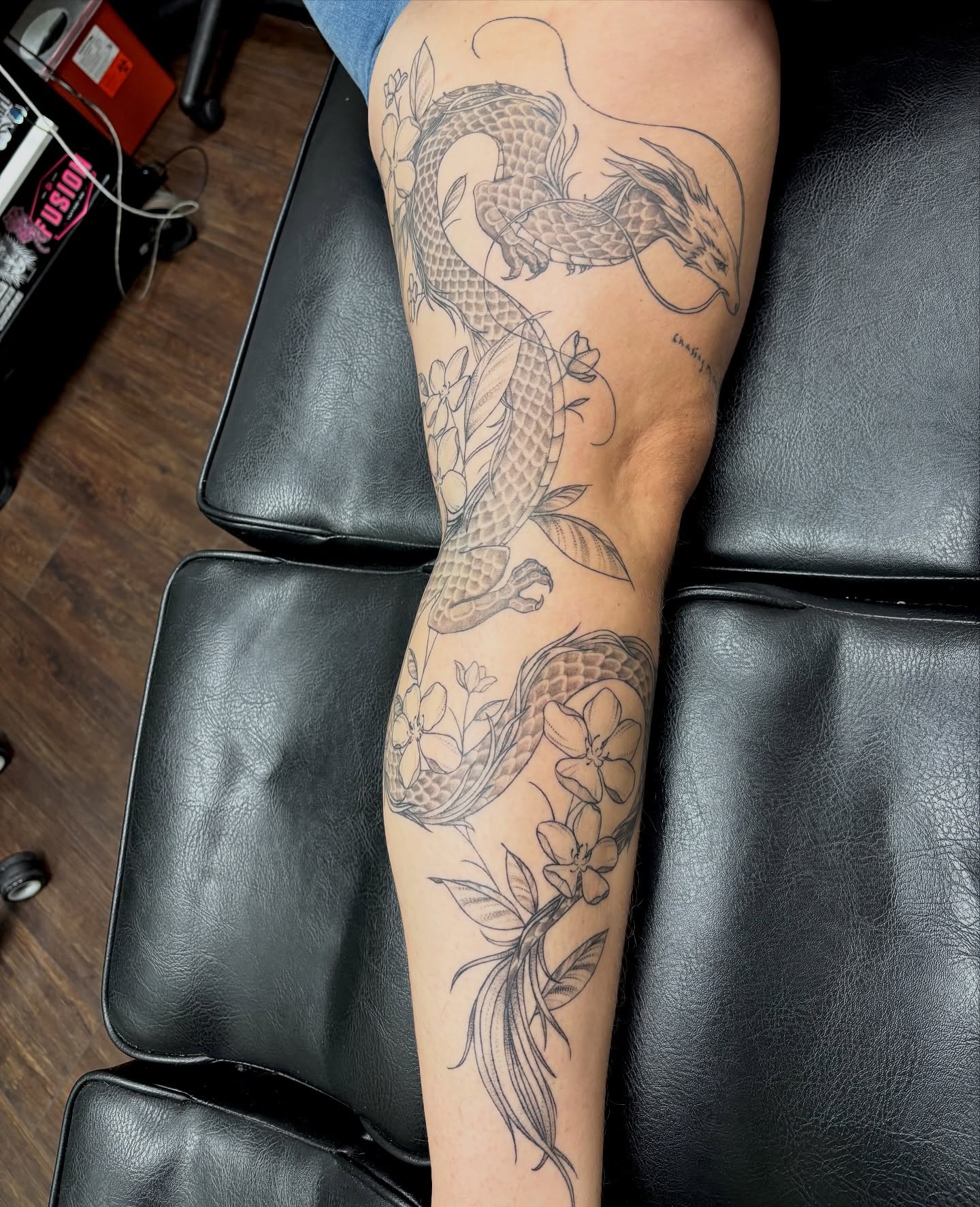 Dragon and flowers black and grey tattoo on the forearm by sydney honn