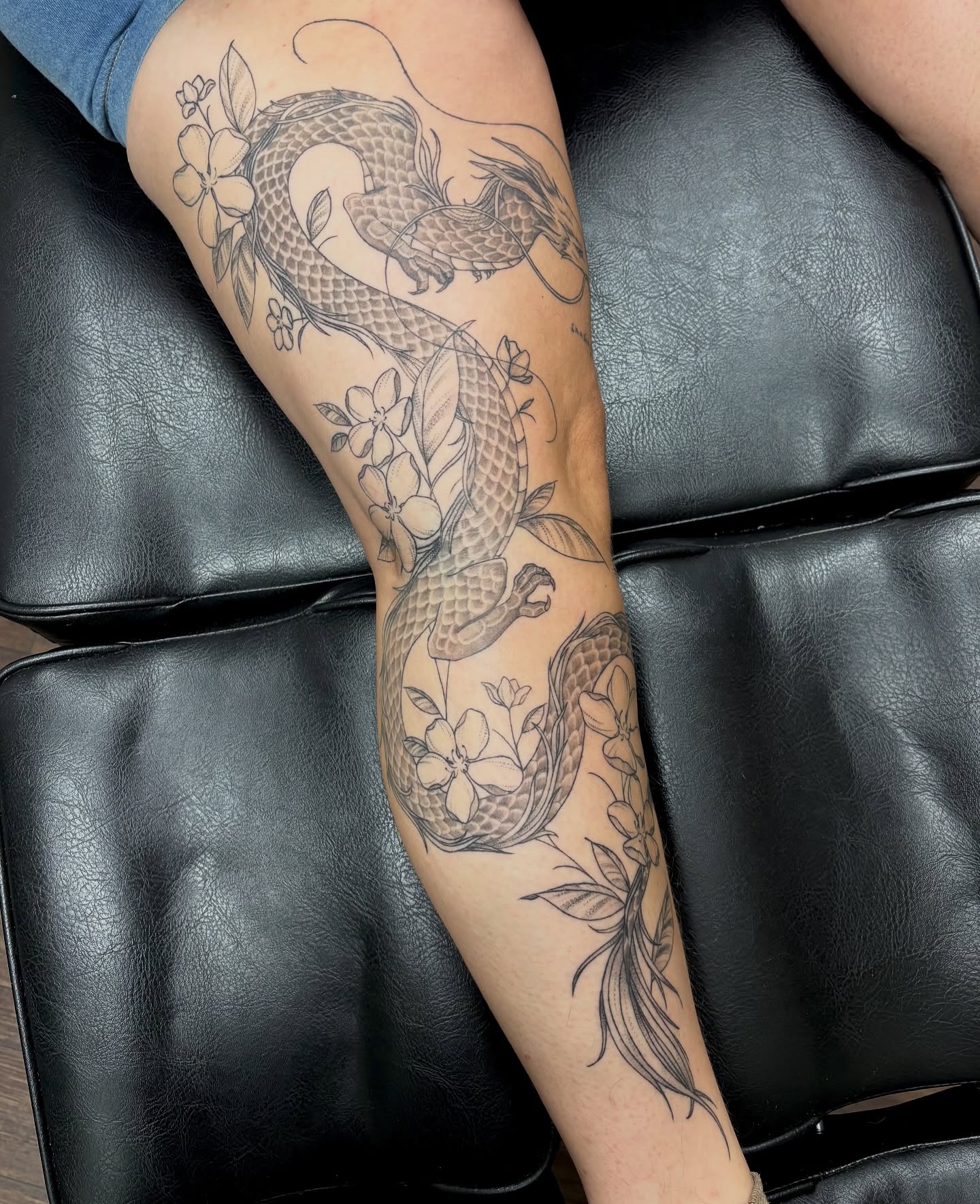 Dragon and flowers black and grey tattoo on the forearm by sydney honn