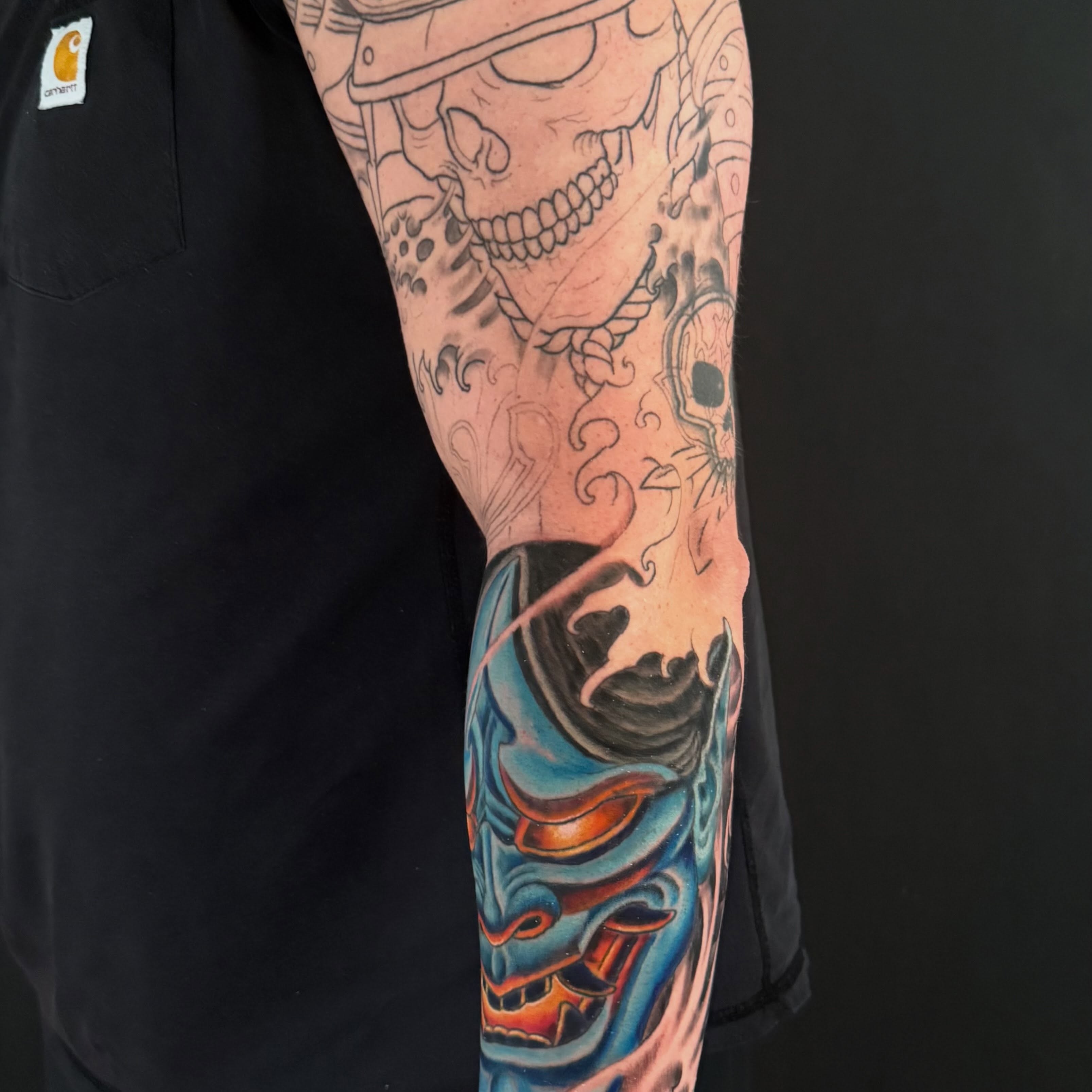 Skull and mask American traditional tattoo on the forearm by Patrick Cornolo