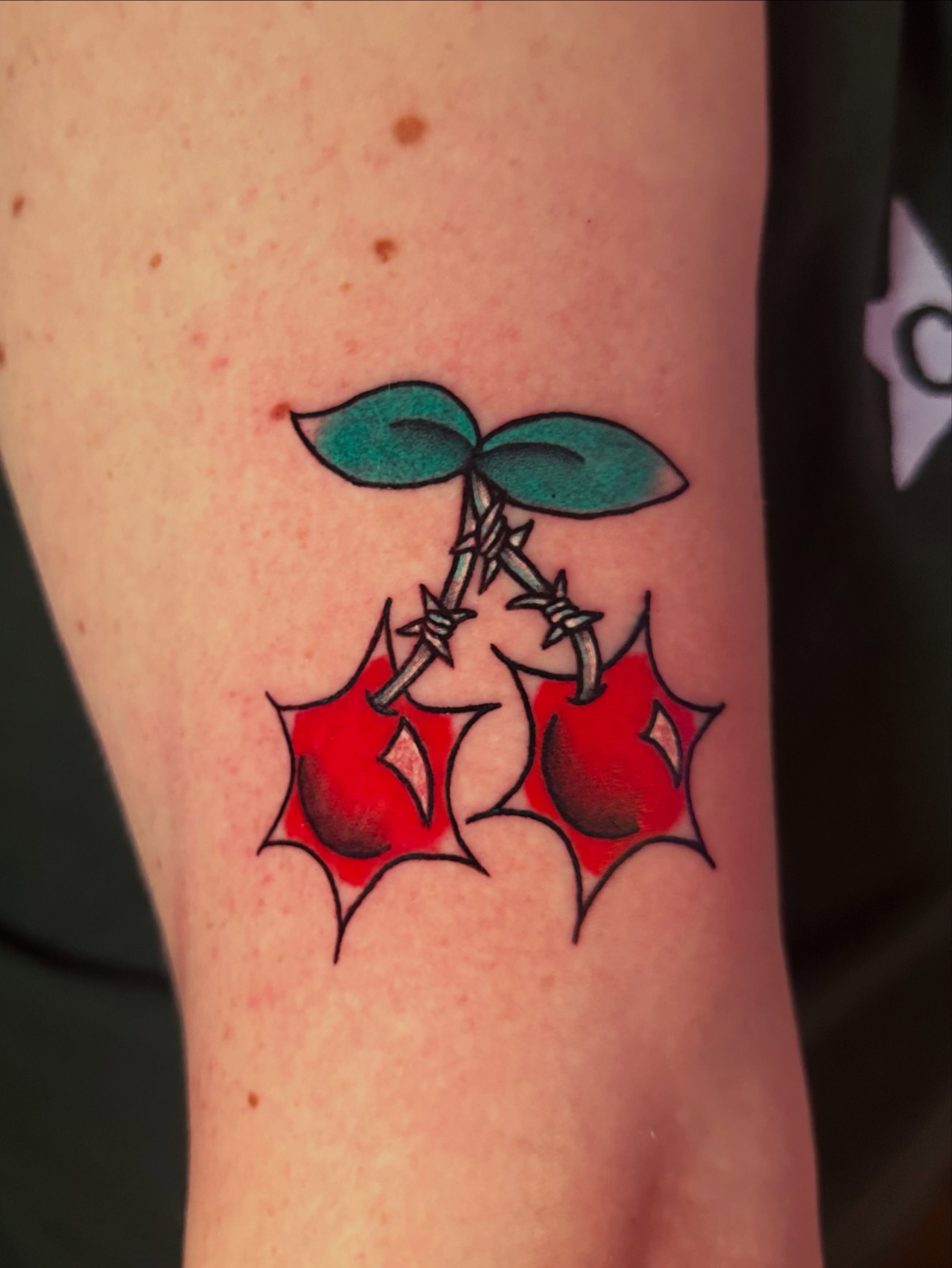 Cherries American traditional tattoo on the forearm by Drew’s Tattoos (NH)