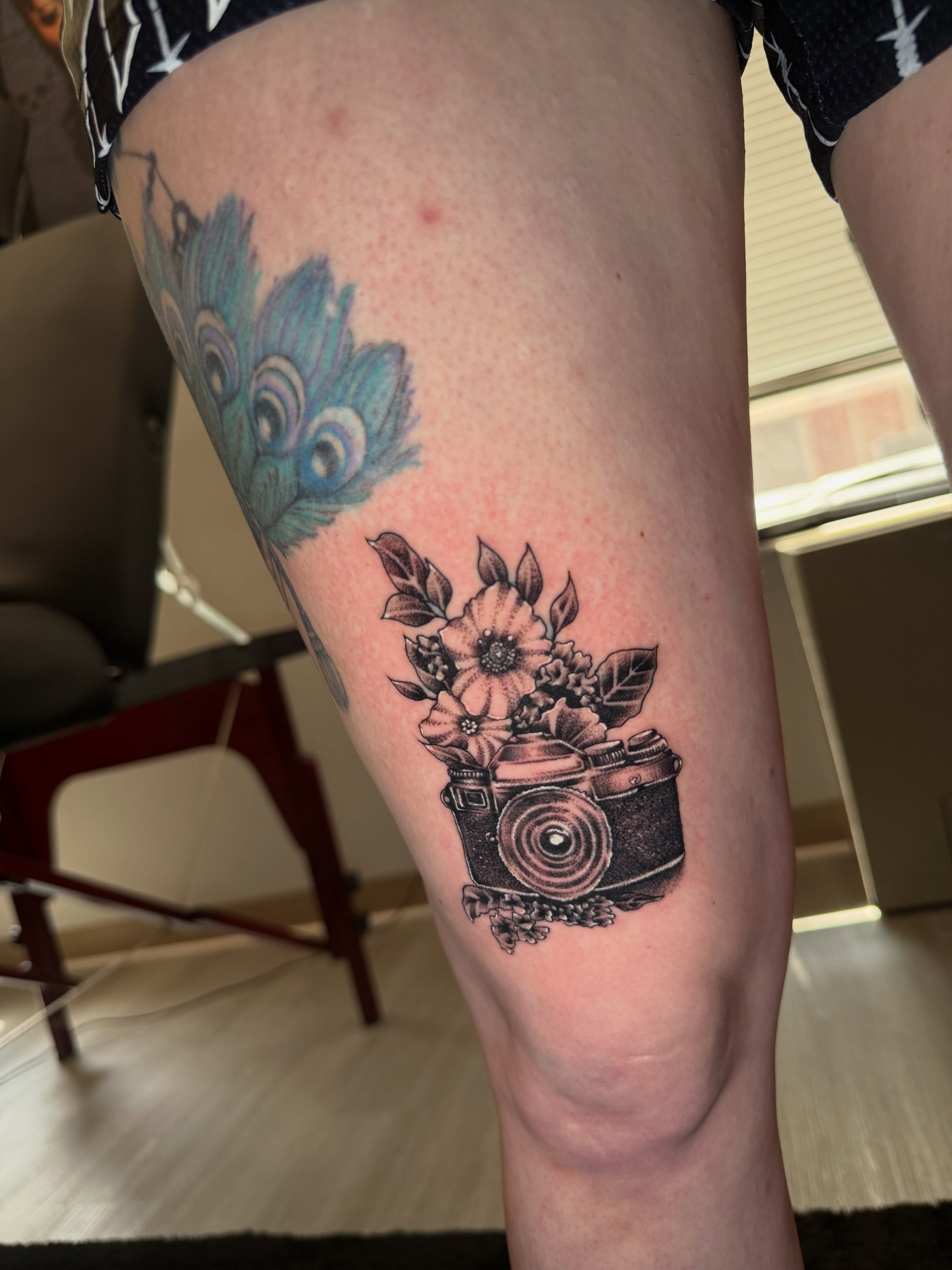 Camera and flowers black and grey tattoo on the thigh by Steve - Tattoo Artist
