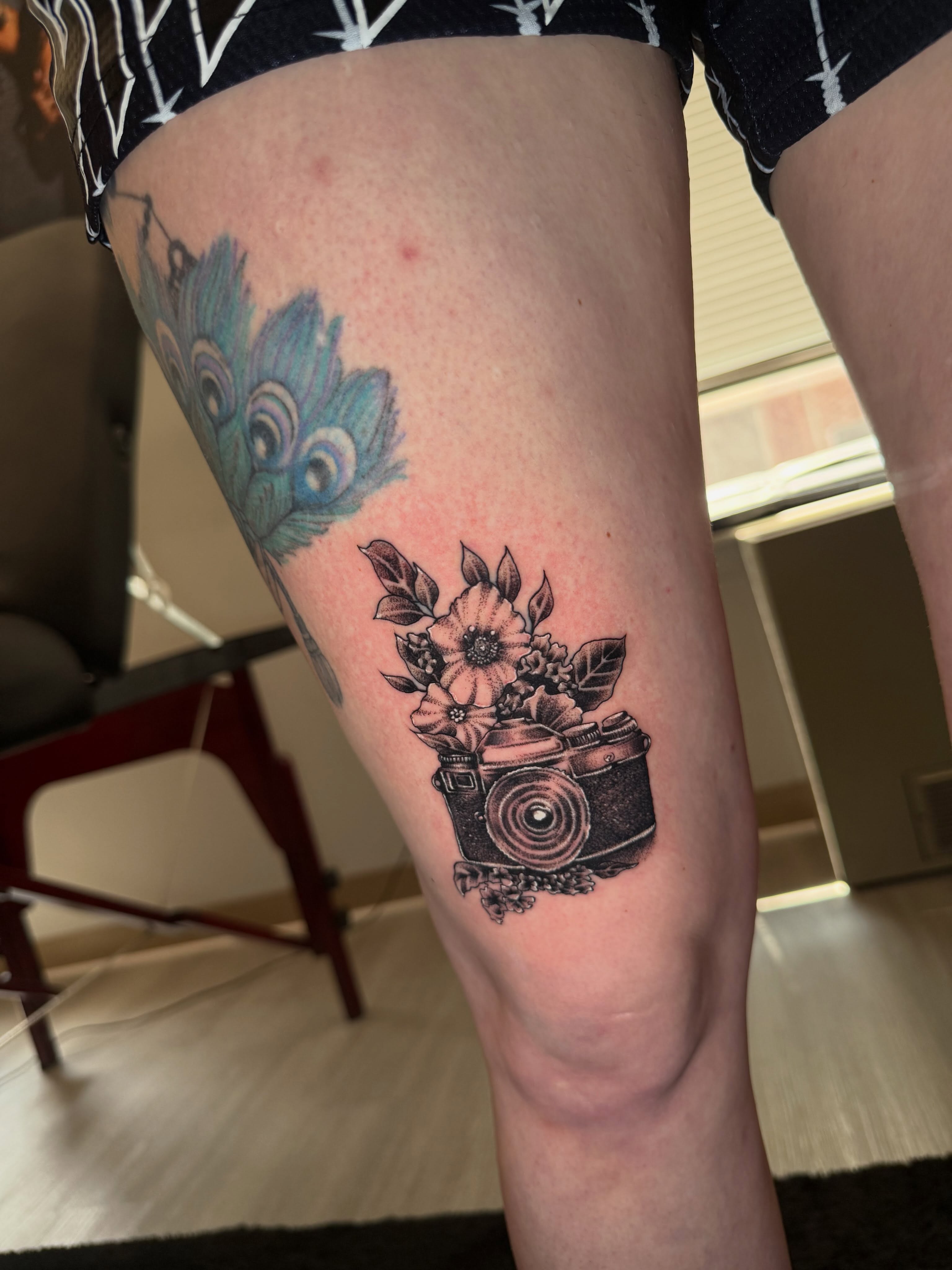Camera and flowers black and grey tattoo on the thigh by Steve - Tattoo Artist