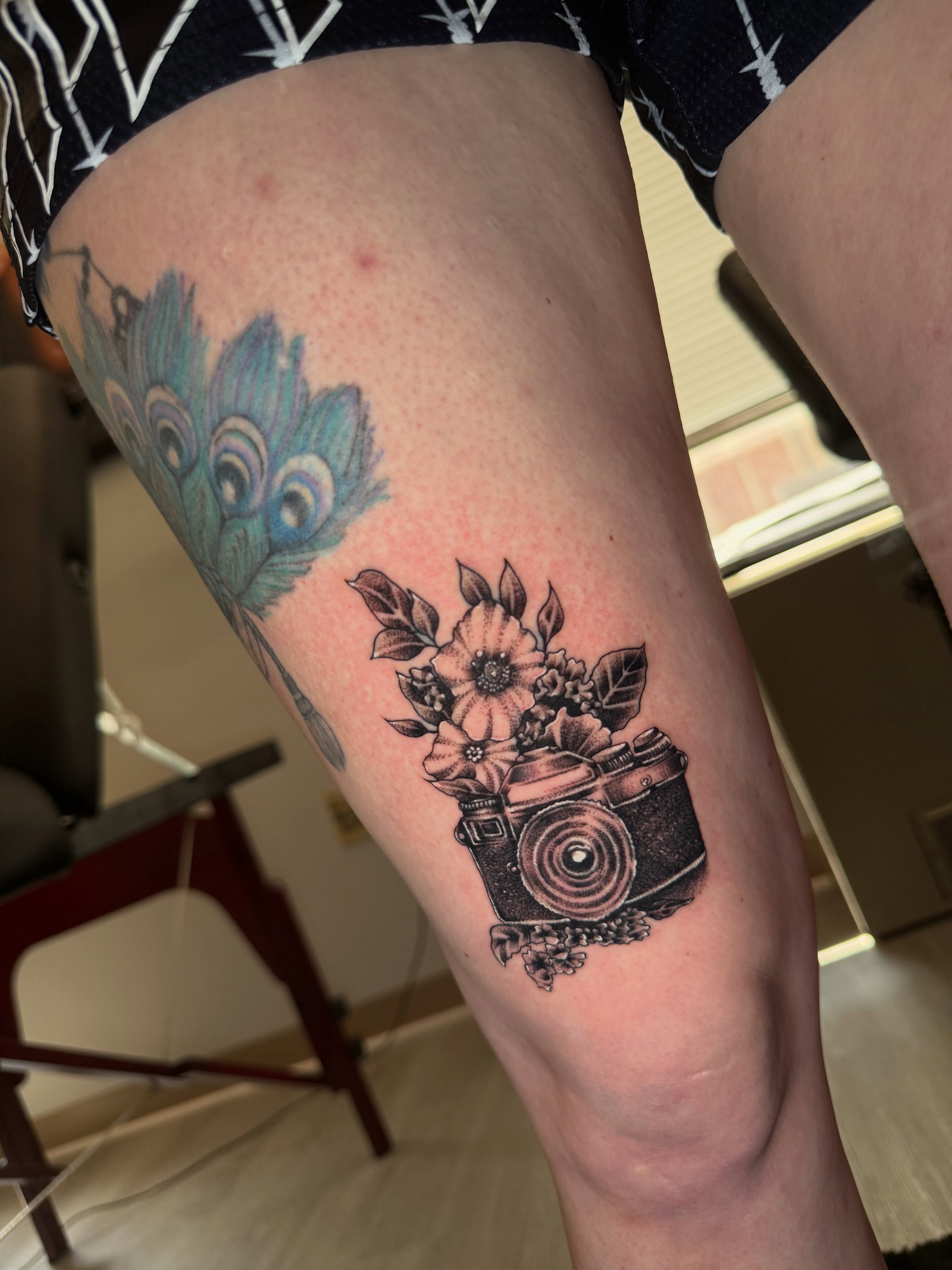 Camera and flowers black and grey tattoo on the thigh by Steve - Tattoo Artist
