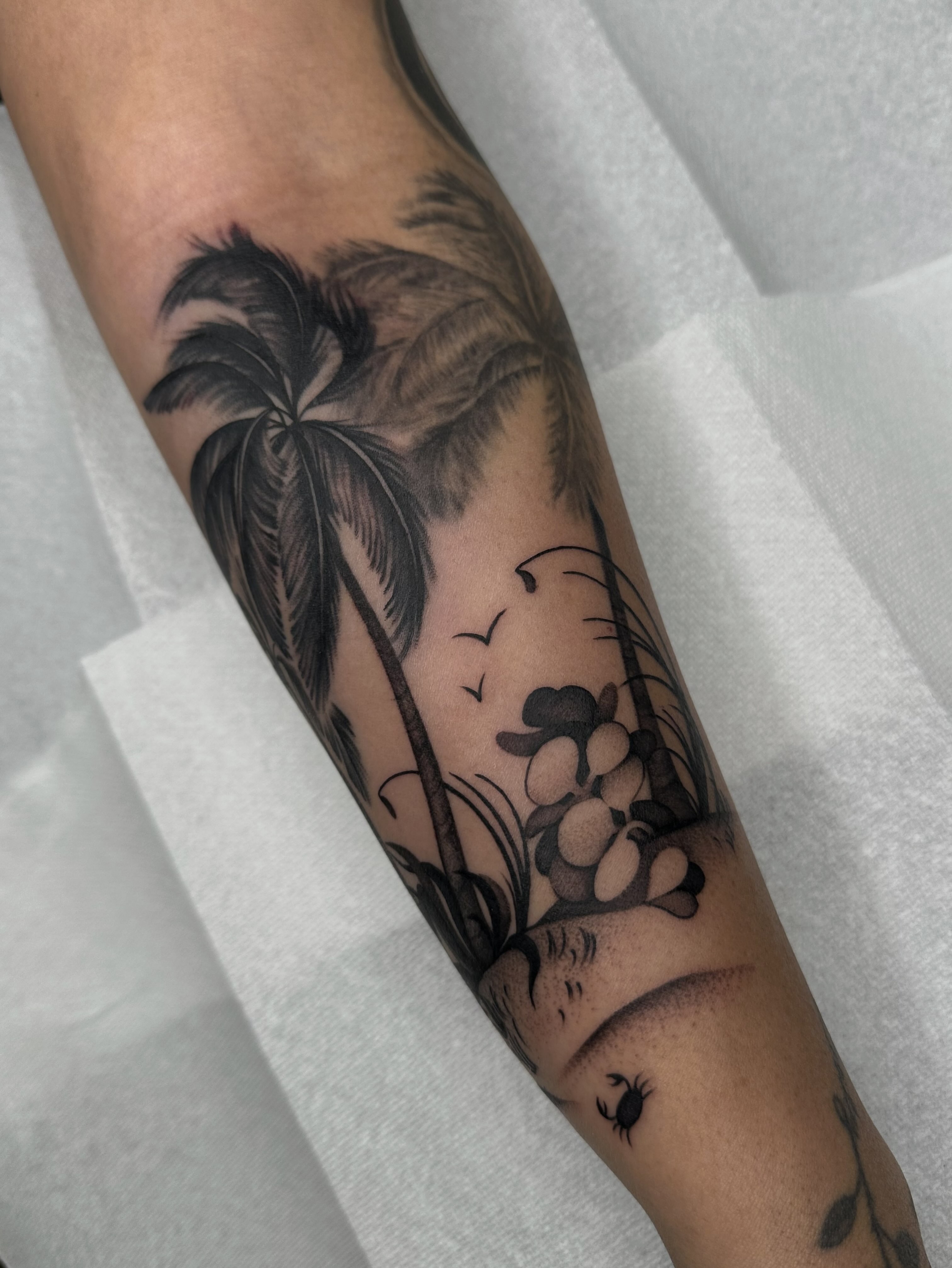 Palm tree and flowers black and grey tattoo on the forearm by Aleksandra
