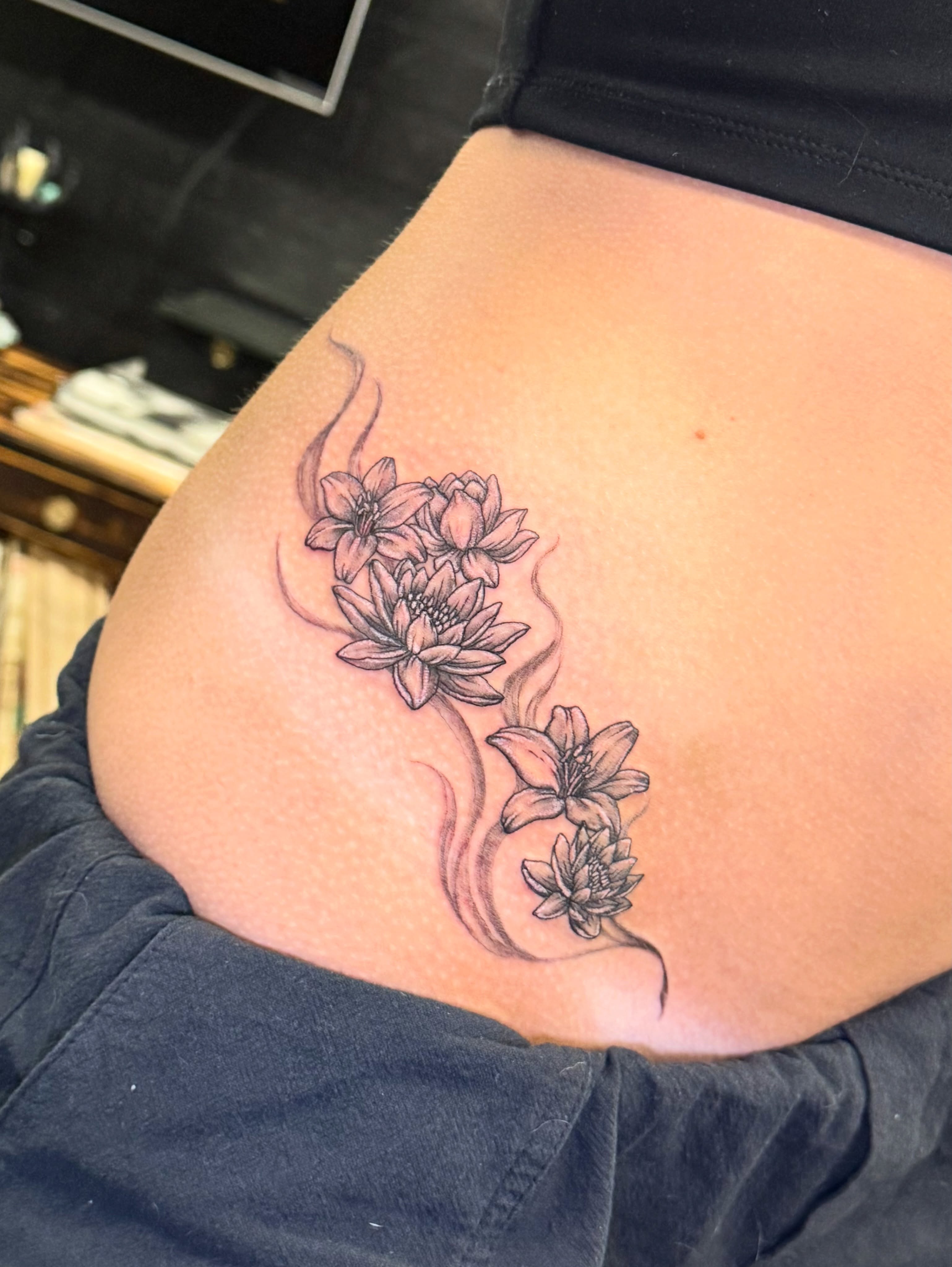 Lotus flowers black and grey tattoo on the thigh by Tyla Pistak, Seattle, Washington