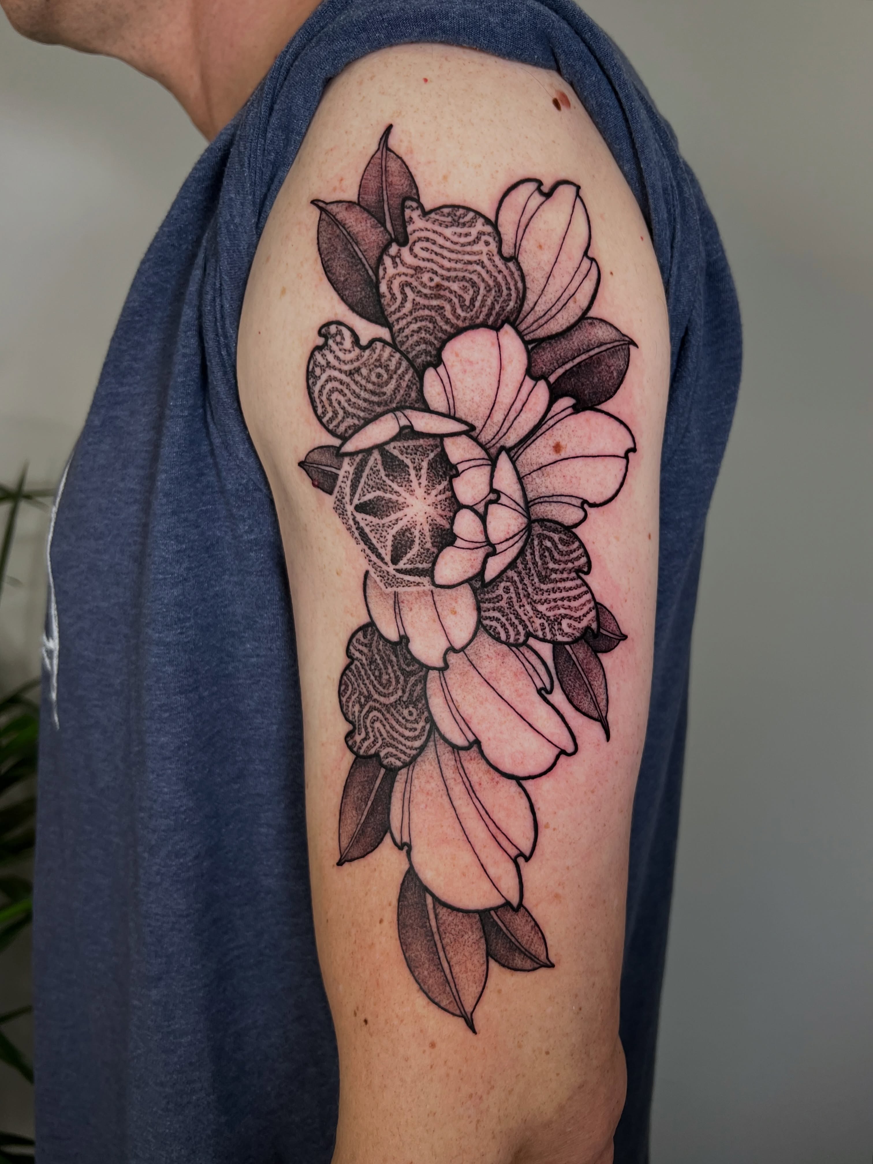 Floral arrangement dotwork tattoo on the upper arm by Riley
