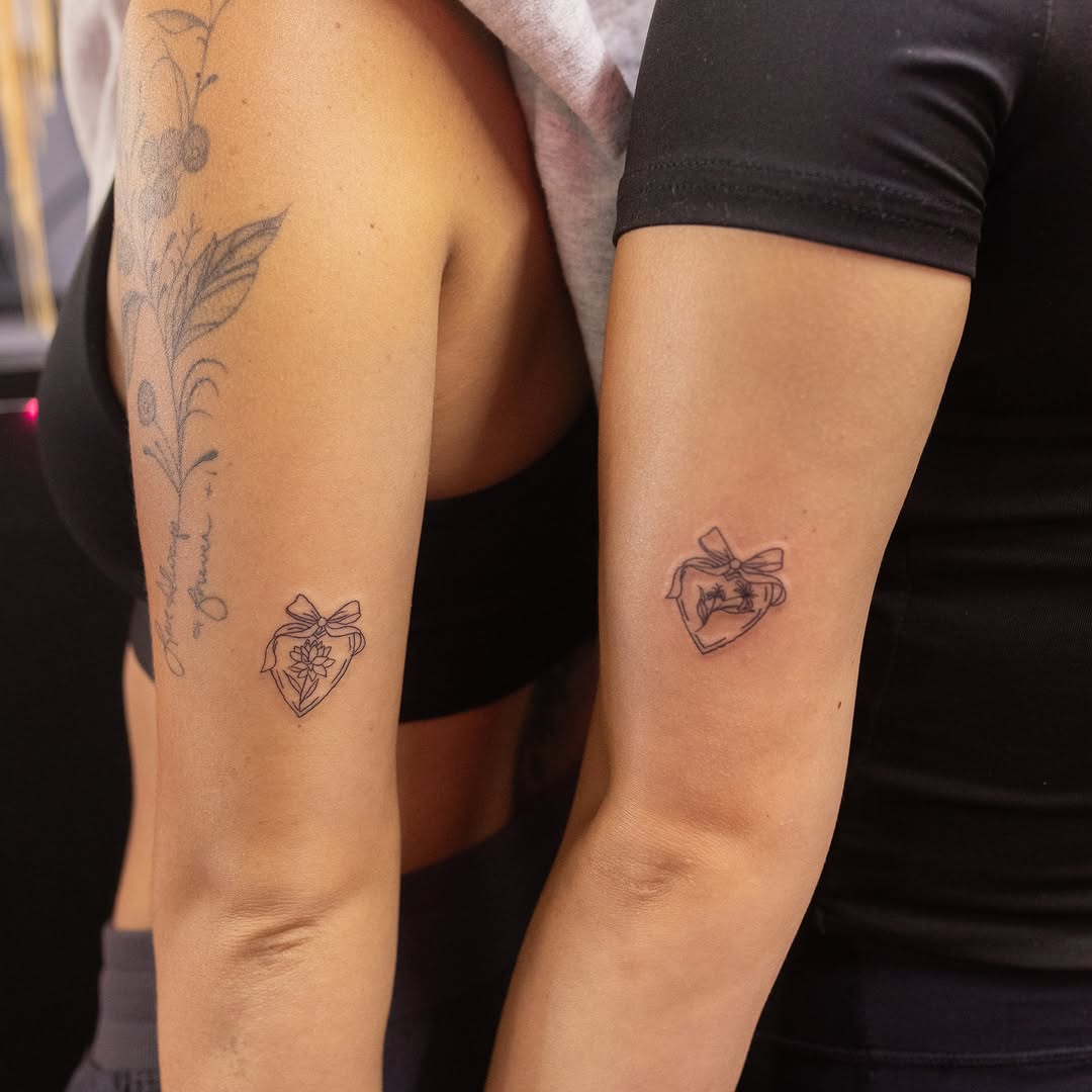 Heart with bow black and grey tattoo on the forearm by Kelsie