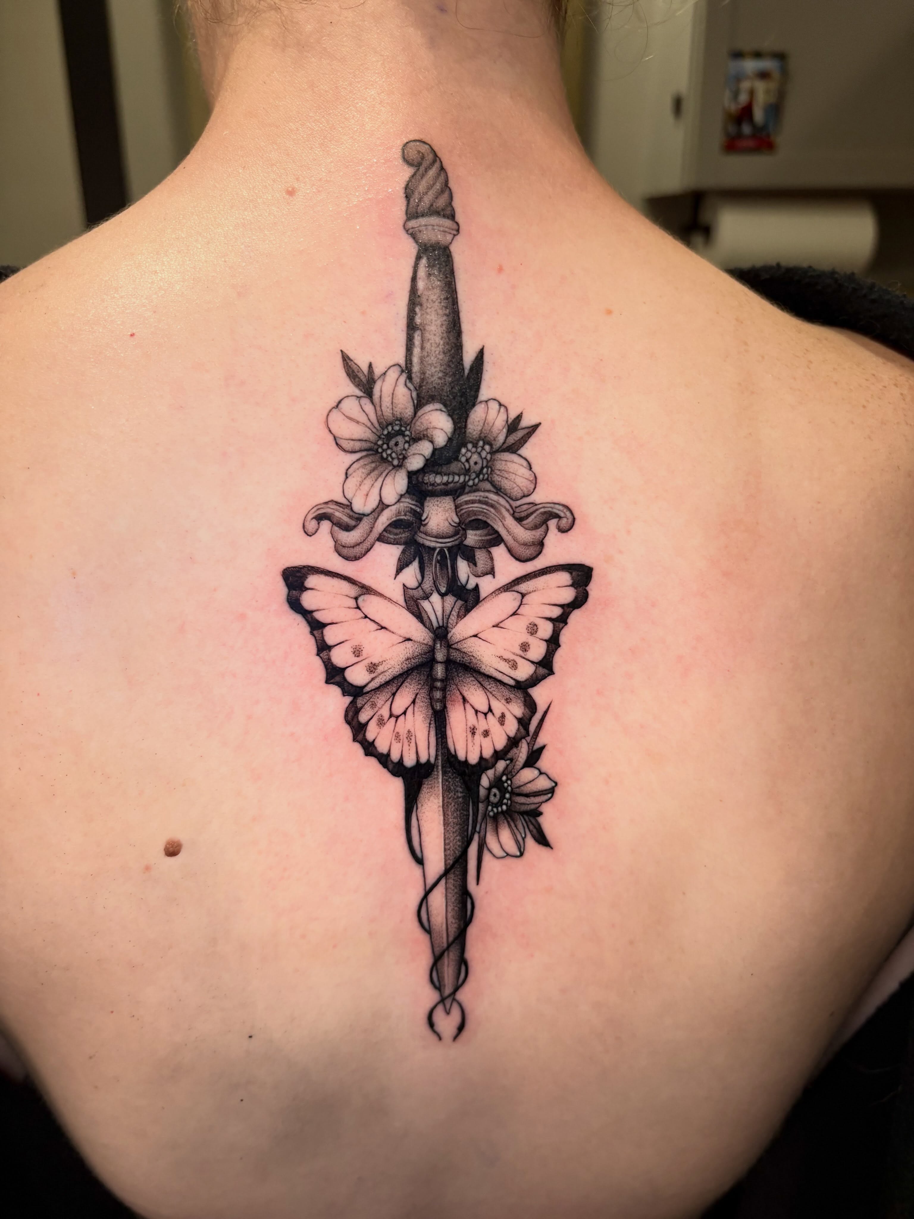Butterfly and dagger black and grey tattoo on the back by Eddie Wolfe