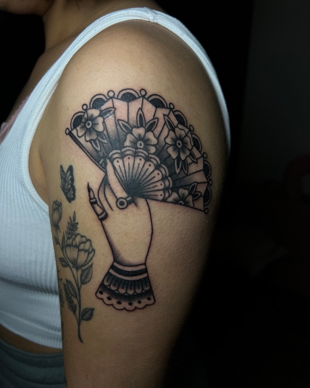 Fan and flowers black and grey tattoo on the shoulder by Iraymi Beltran