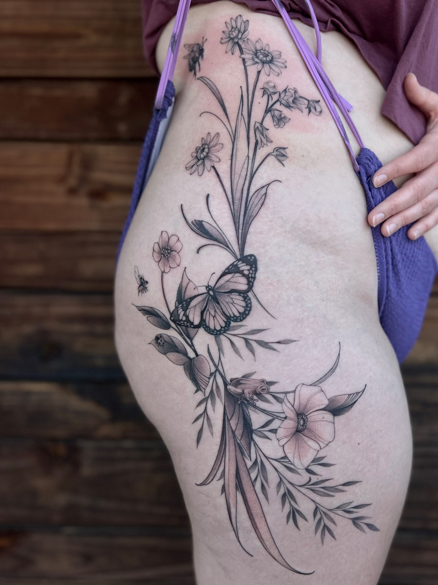 Floral arrangement with butterfly black and grey tattoo on the thigh by Tehnaya