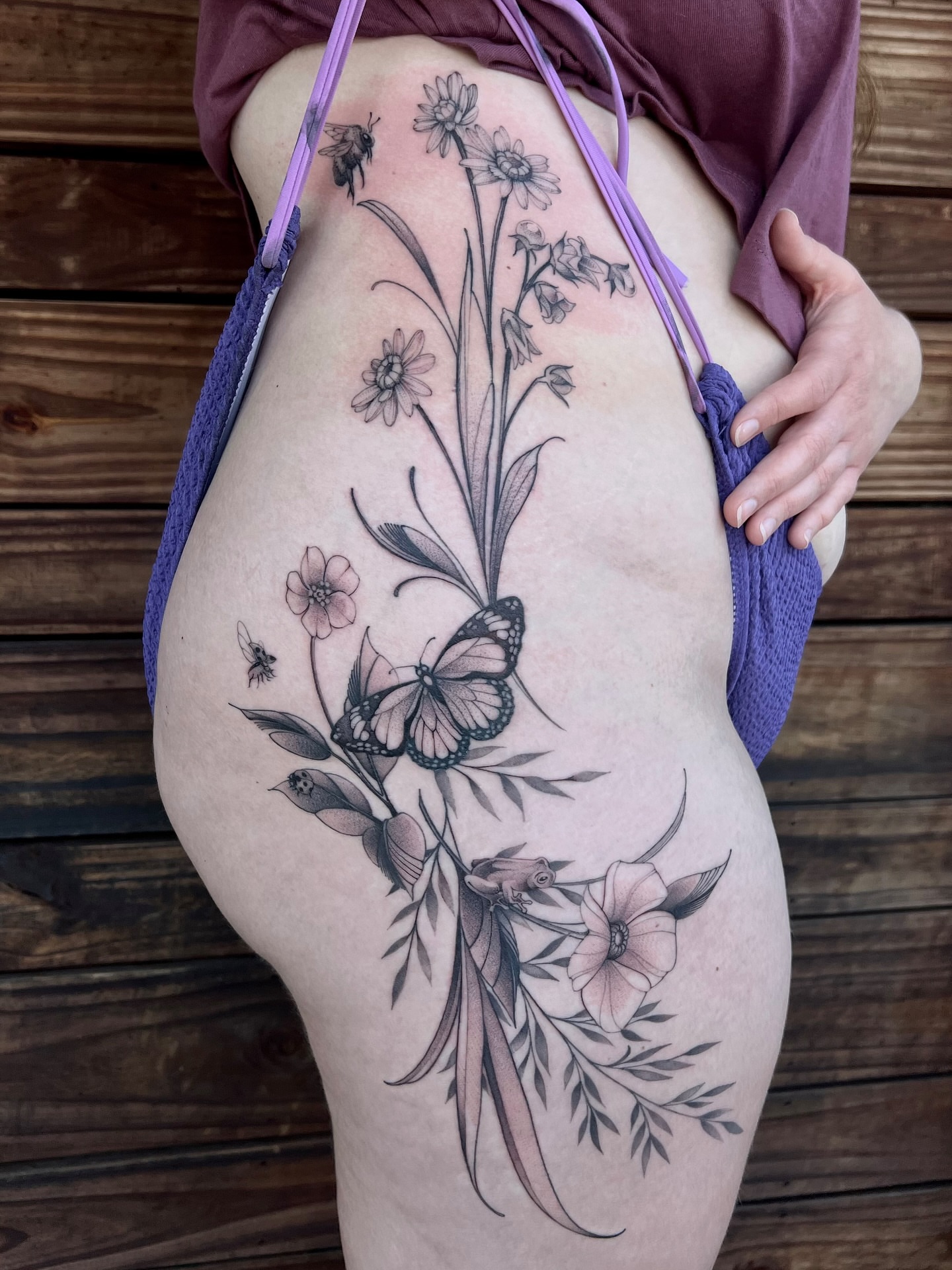 Floral arrangement with butterfly black and grey tattoo on the thigh by Tehnaya