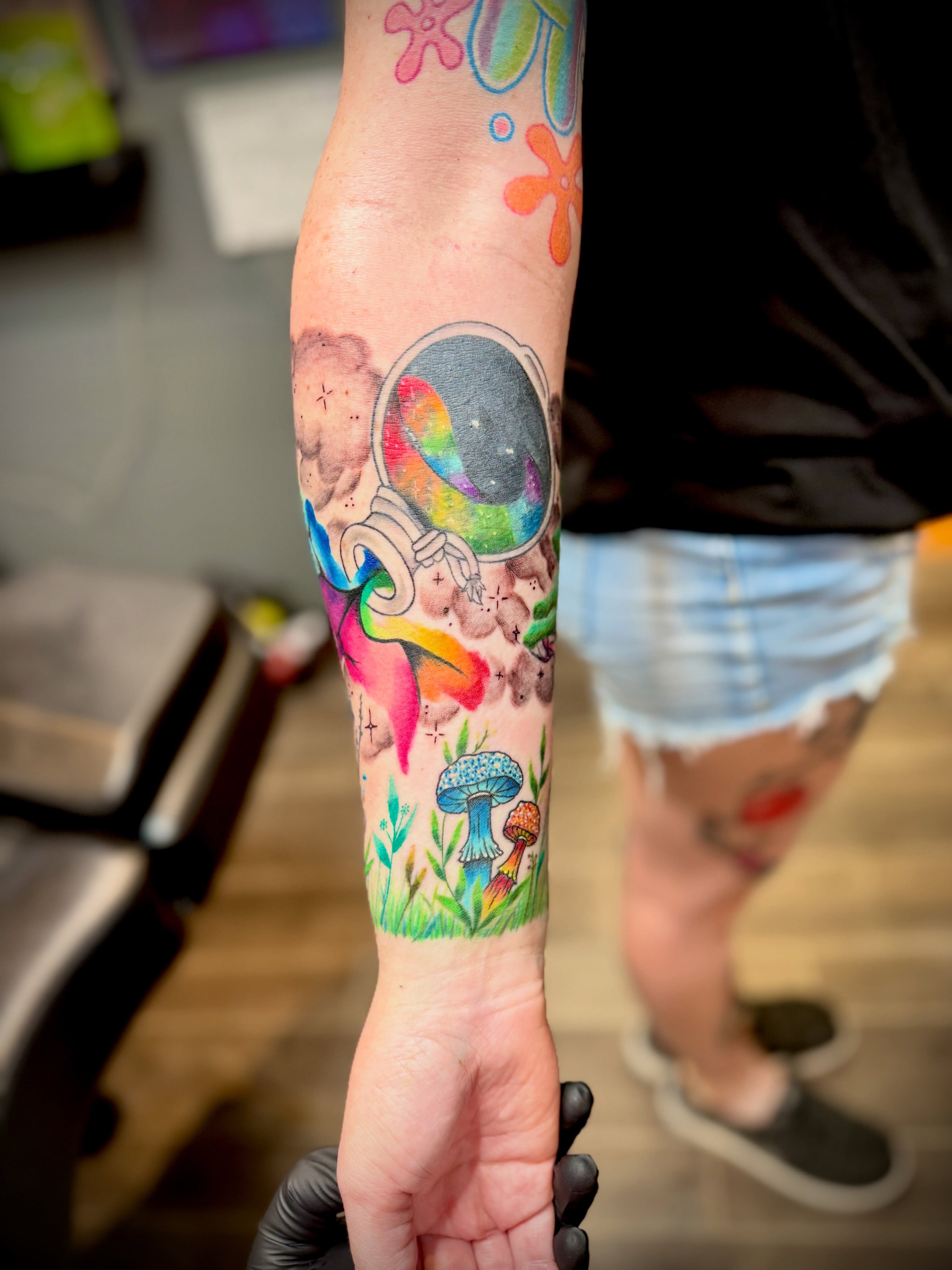Astronaut and mushrooms new school tattoo on the forearm by Kacy Blalock
