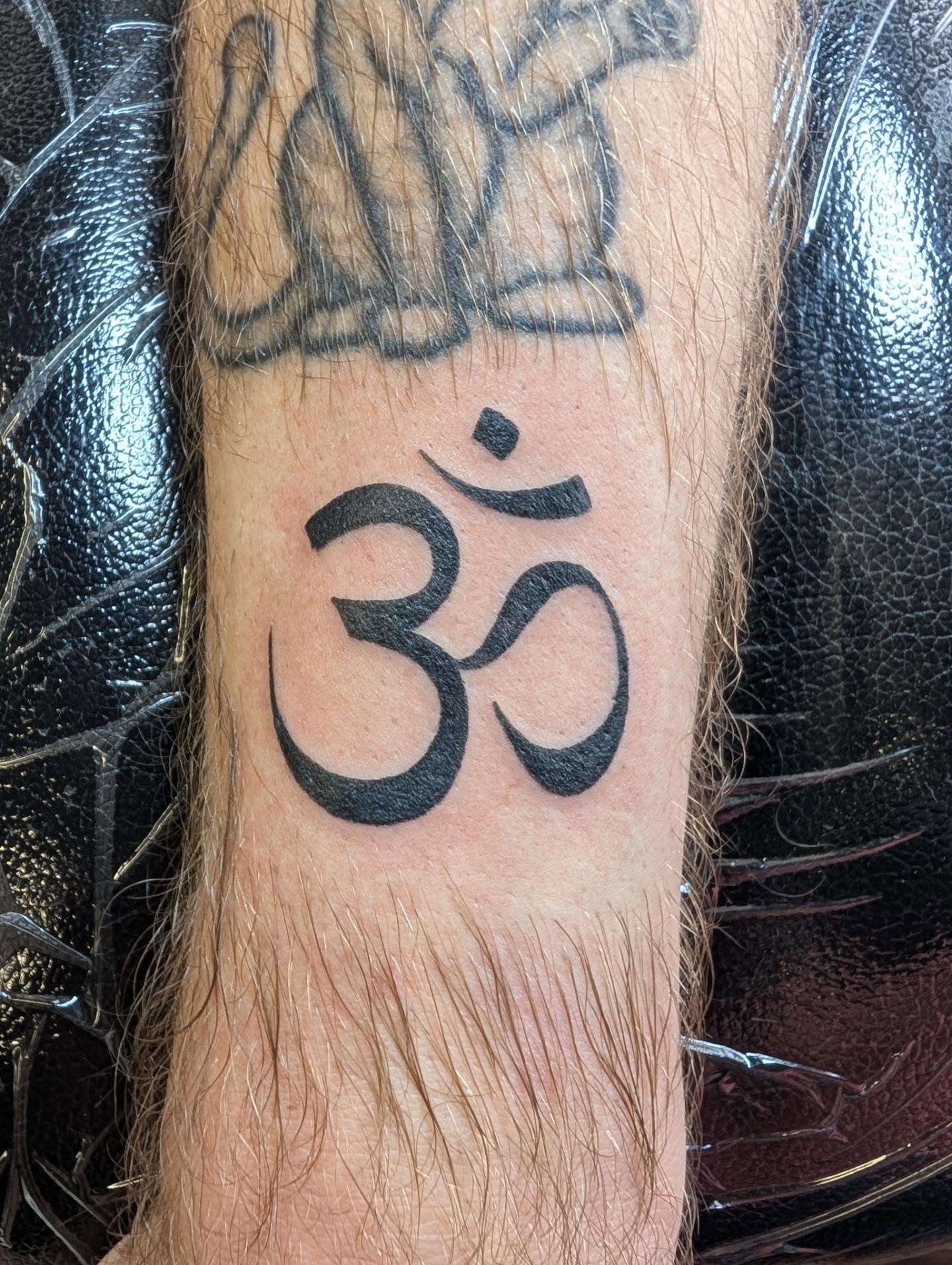 Om symbol black and grey tattoo on the forearm by Chad Nuber