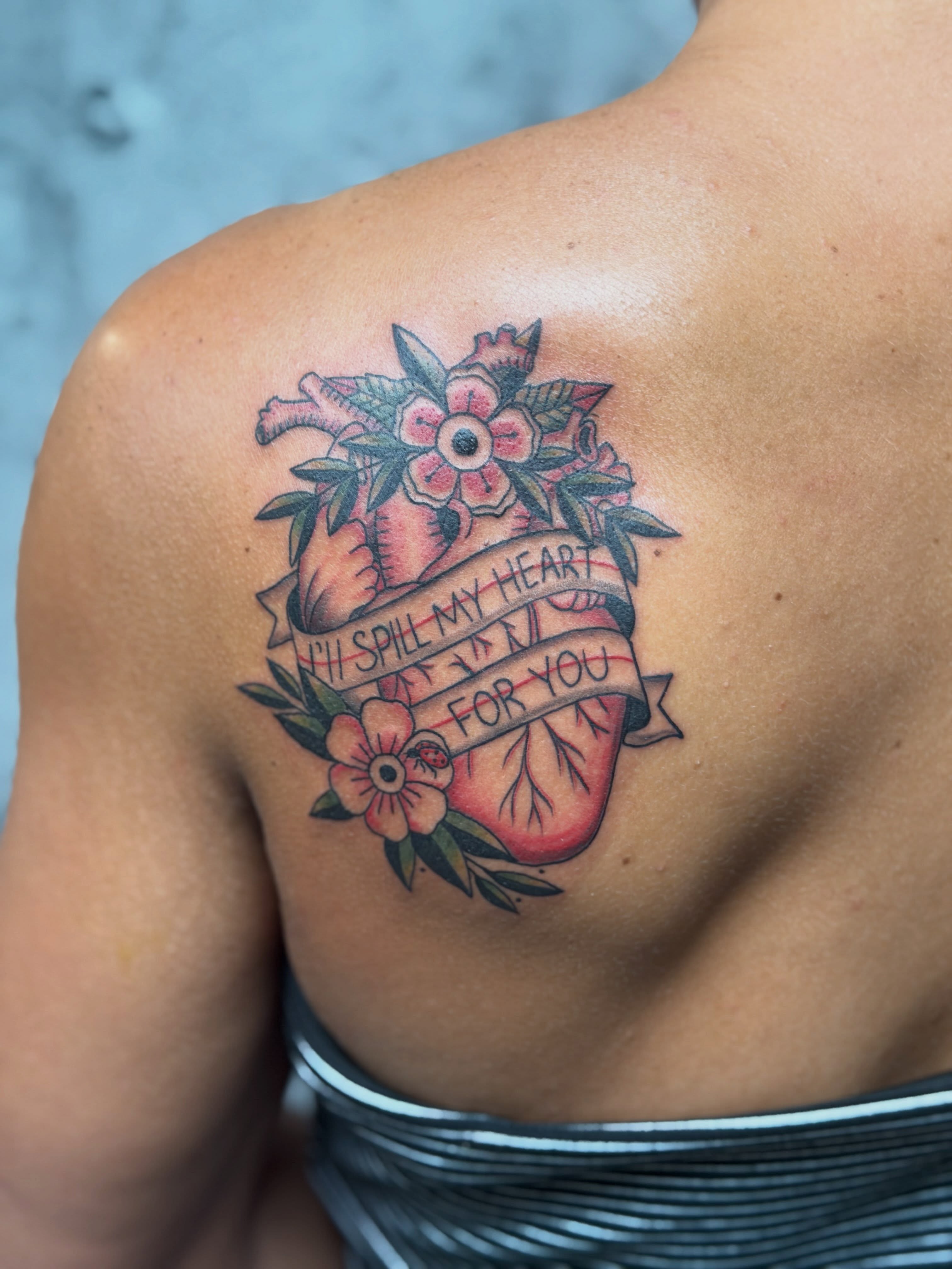 Heart with flowers American traditional tattoo on the shoulder by Aura Noire
