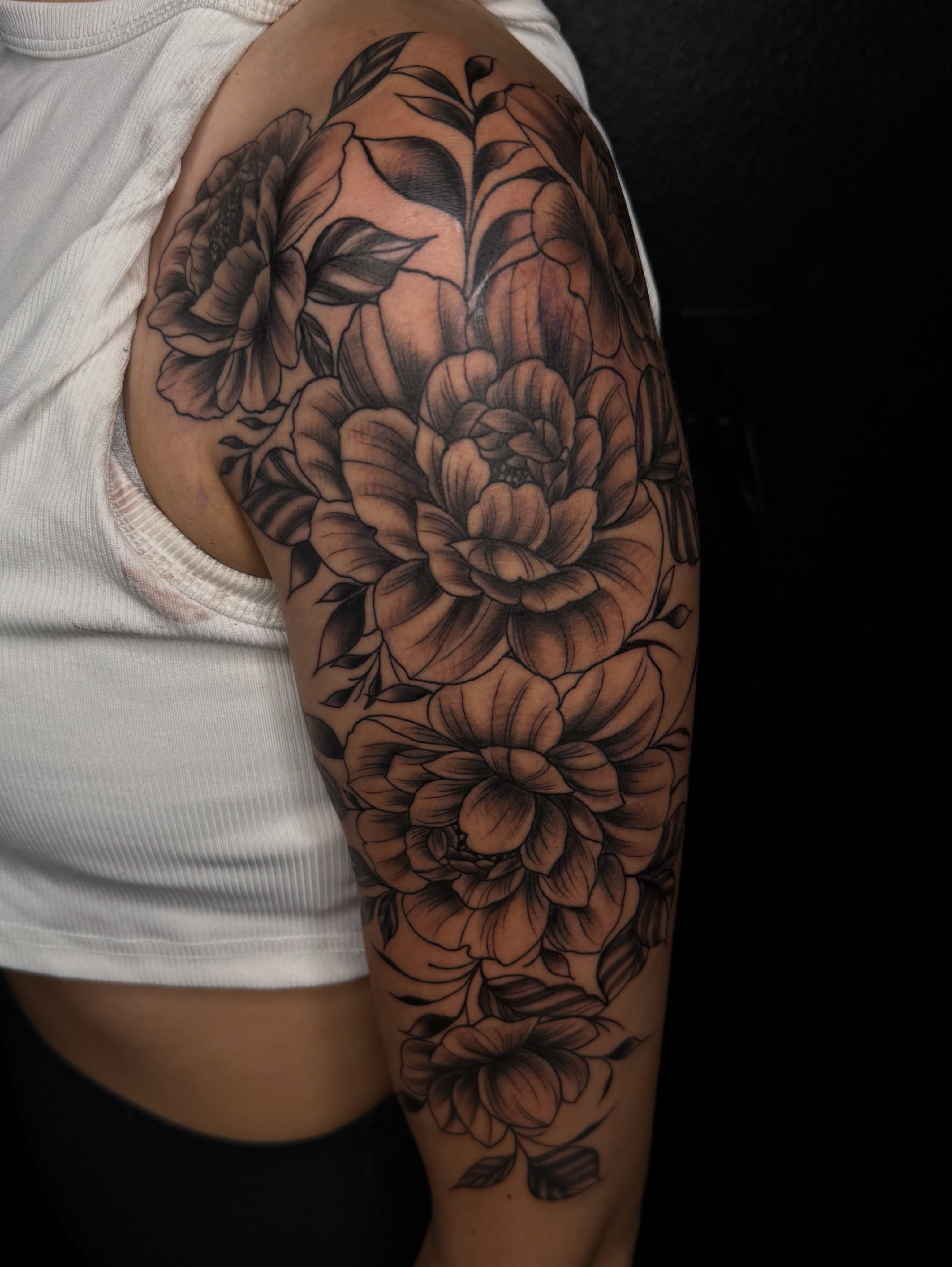 Floral bouquet black and grey tattoo on the upper arm by Elijah East