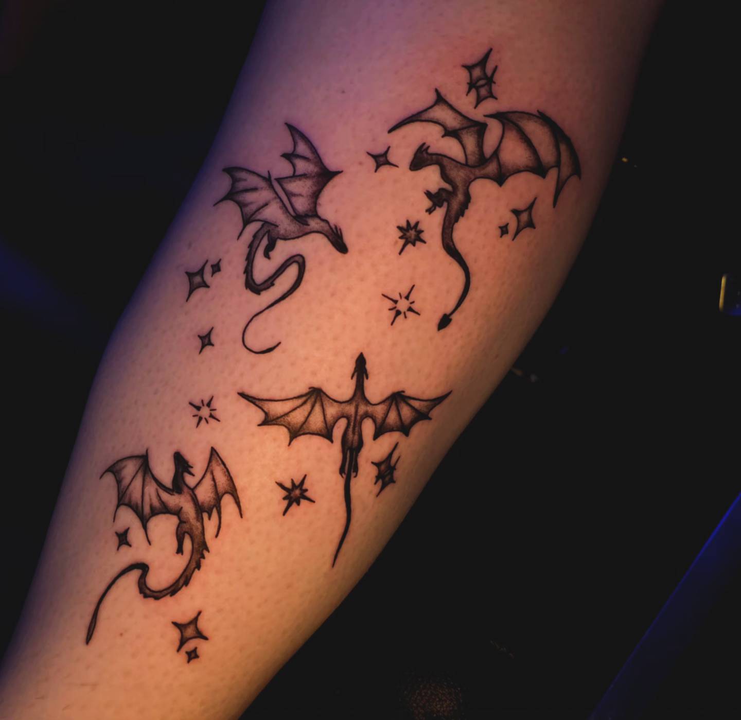 Dragons and stars black and grey tattoo on the forearm by Karley Michelle Moody