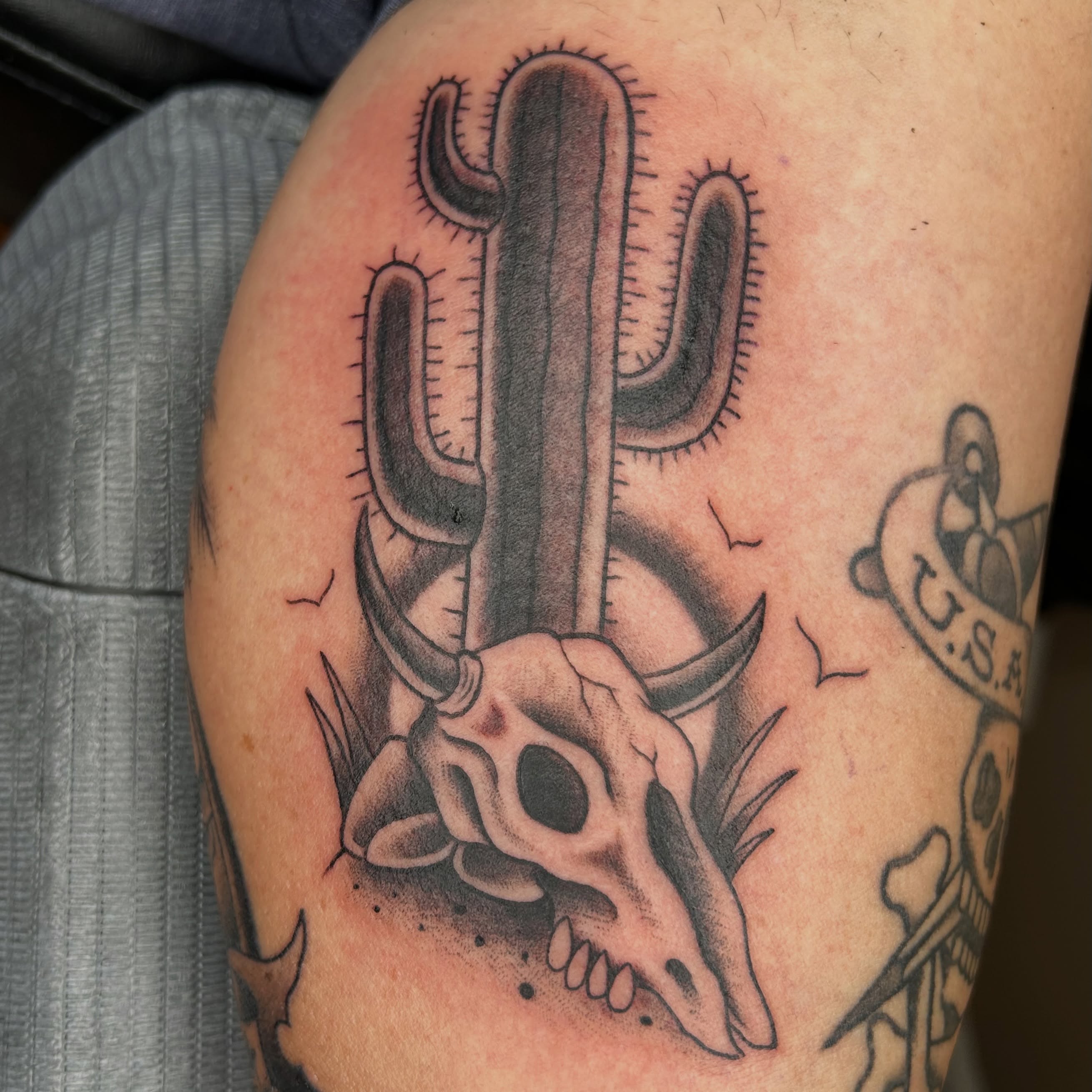 Cactus and skull American traditional tattoo on the upper arm by Alex Byrne