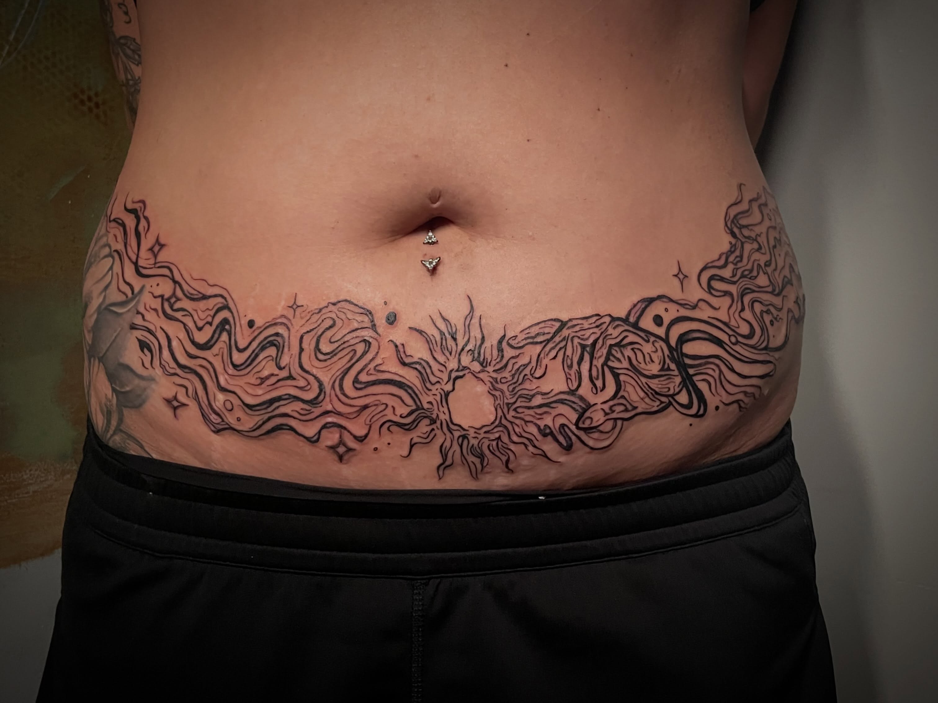 Abstract waves black and grey tattoo on the torso by Hannah Copeskey