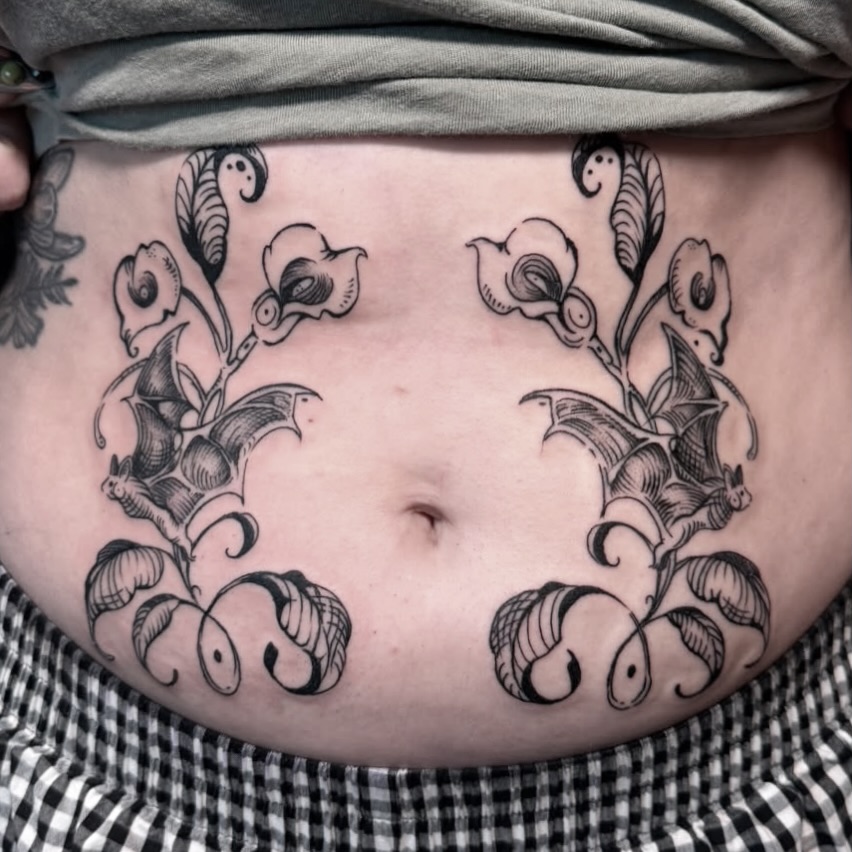 Calla lilies and bats black and grey tattoo on the torso by Allyson Blessing Tattoos