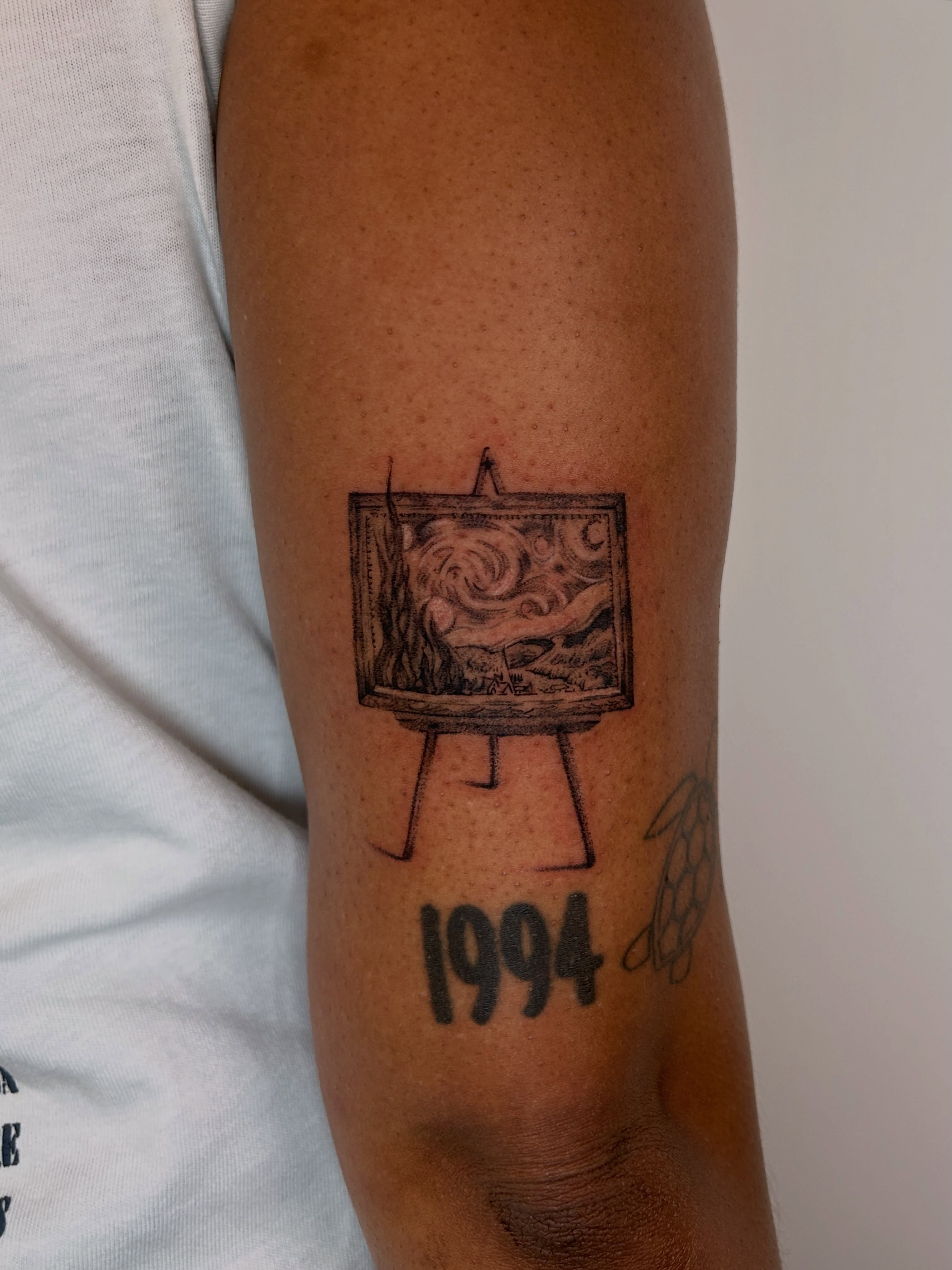 Painting on easel black and grey tattoo on the forearm by J