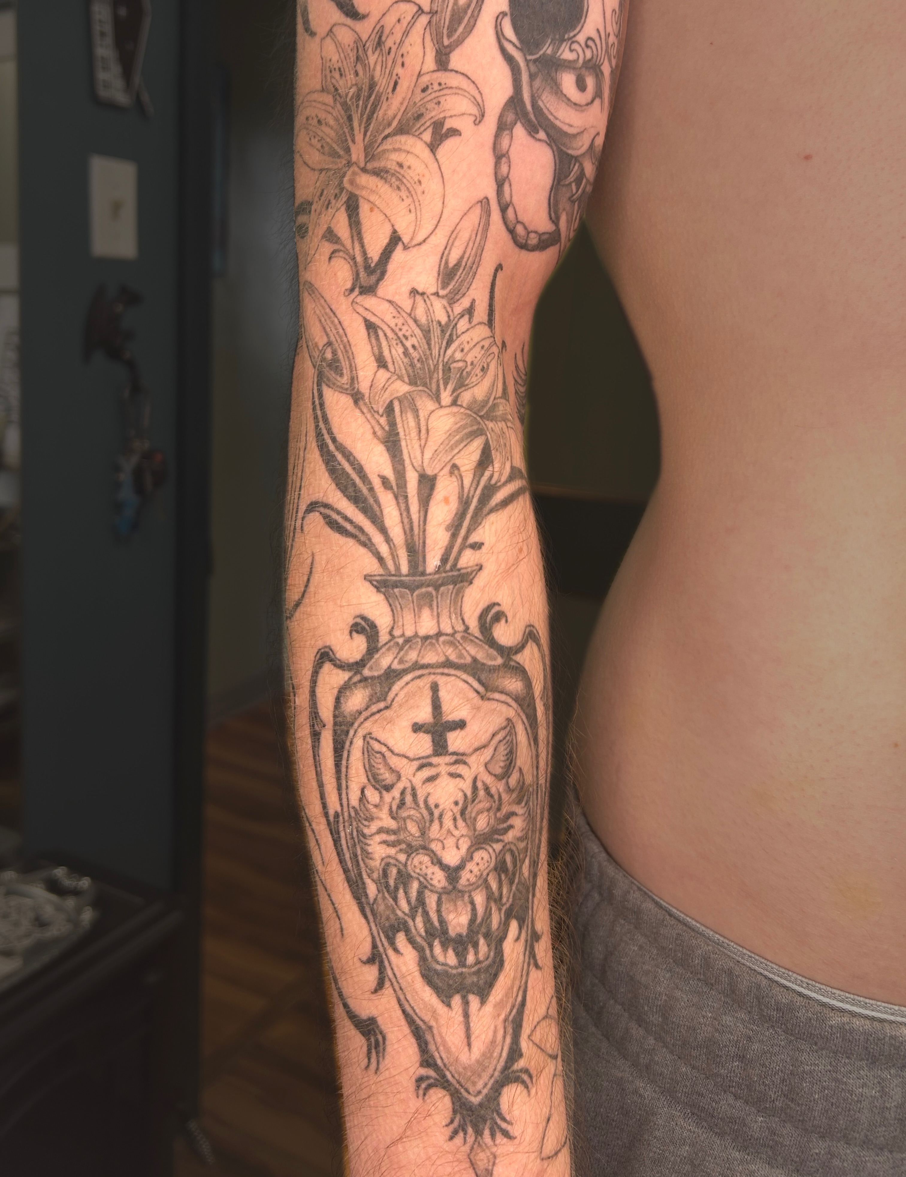 Lilies and demon dark realism tattoo on the forearm by Magnus