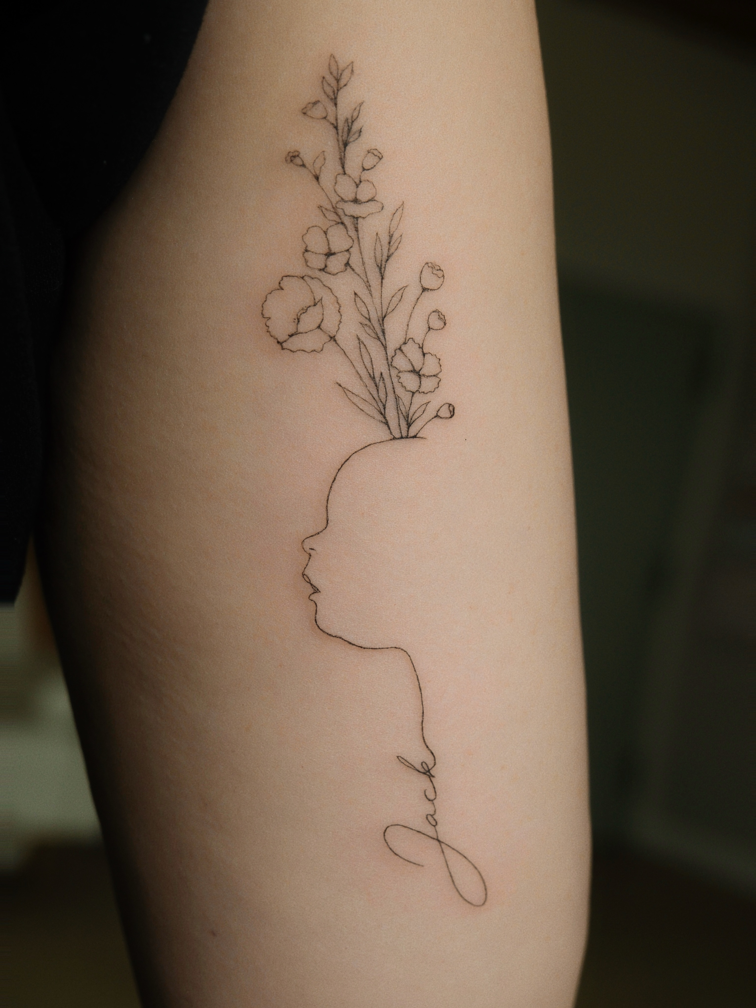 Profile silhouette with flowers fine line tattoo on the forearm by Victoria