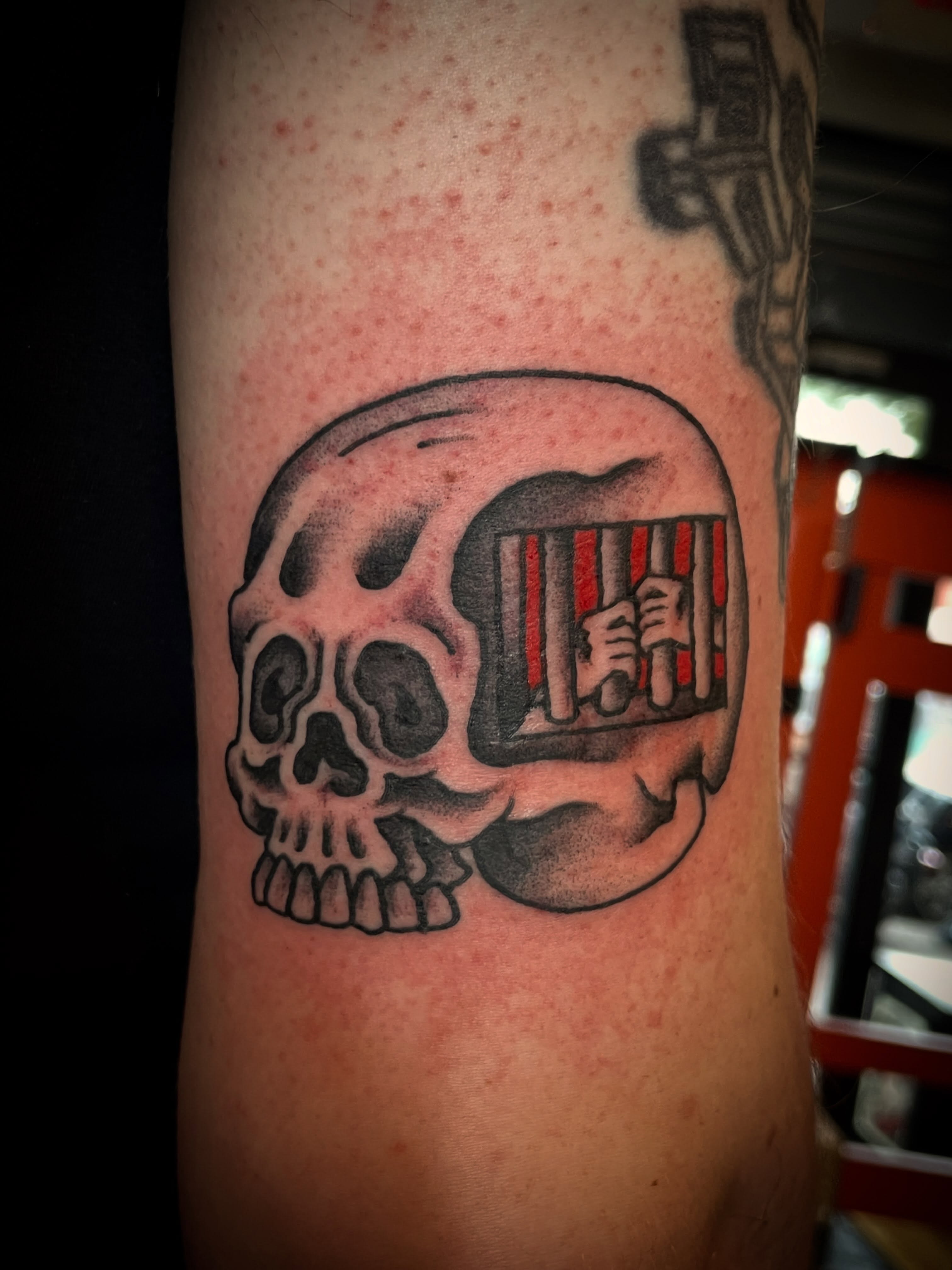 Skull with cage black and grey tattoo on the forearm by Nick Wallin