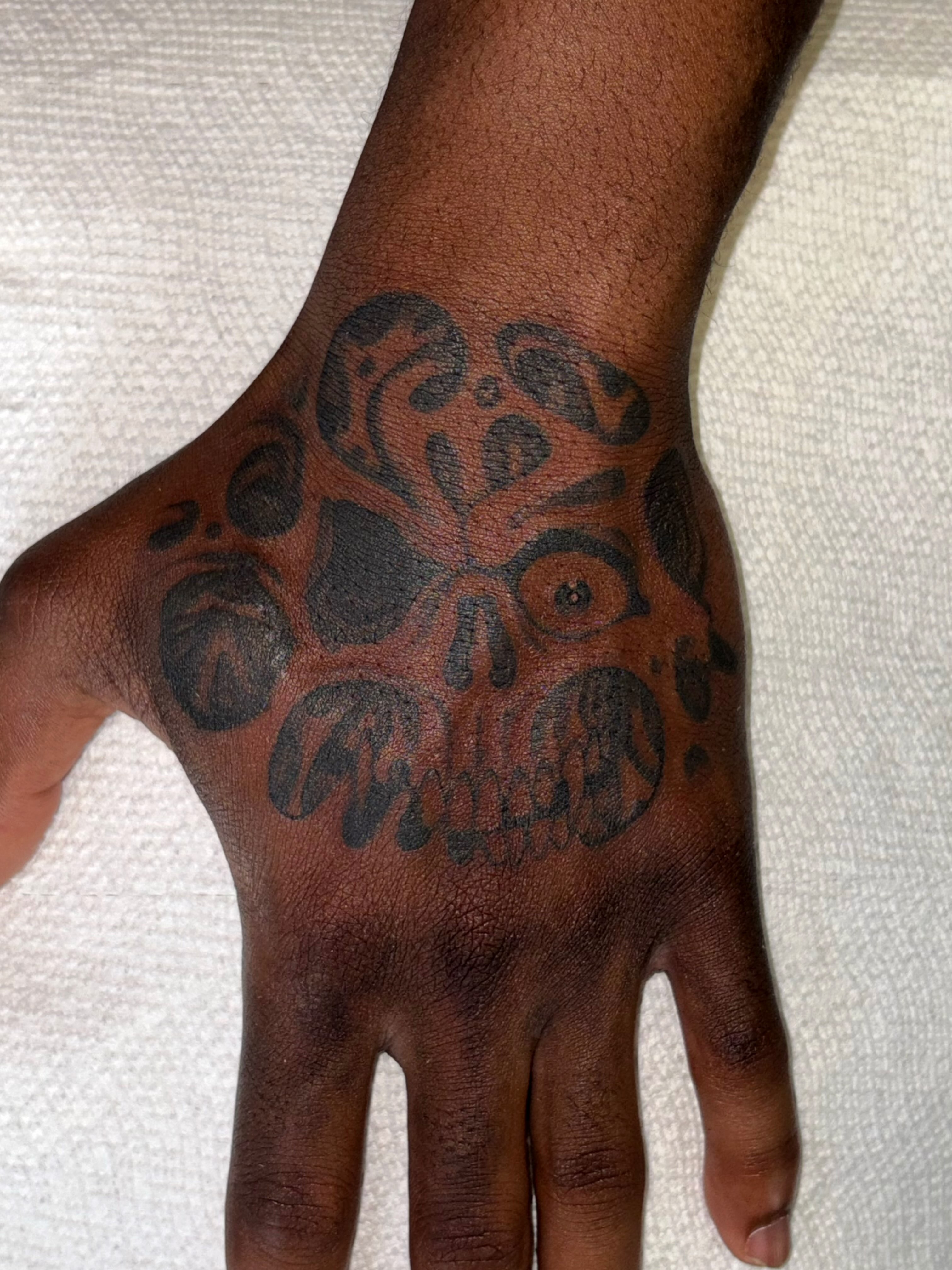 Skull black and grey tattoo on the hand by Brendan Smith