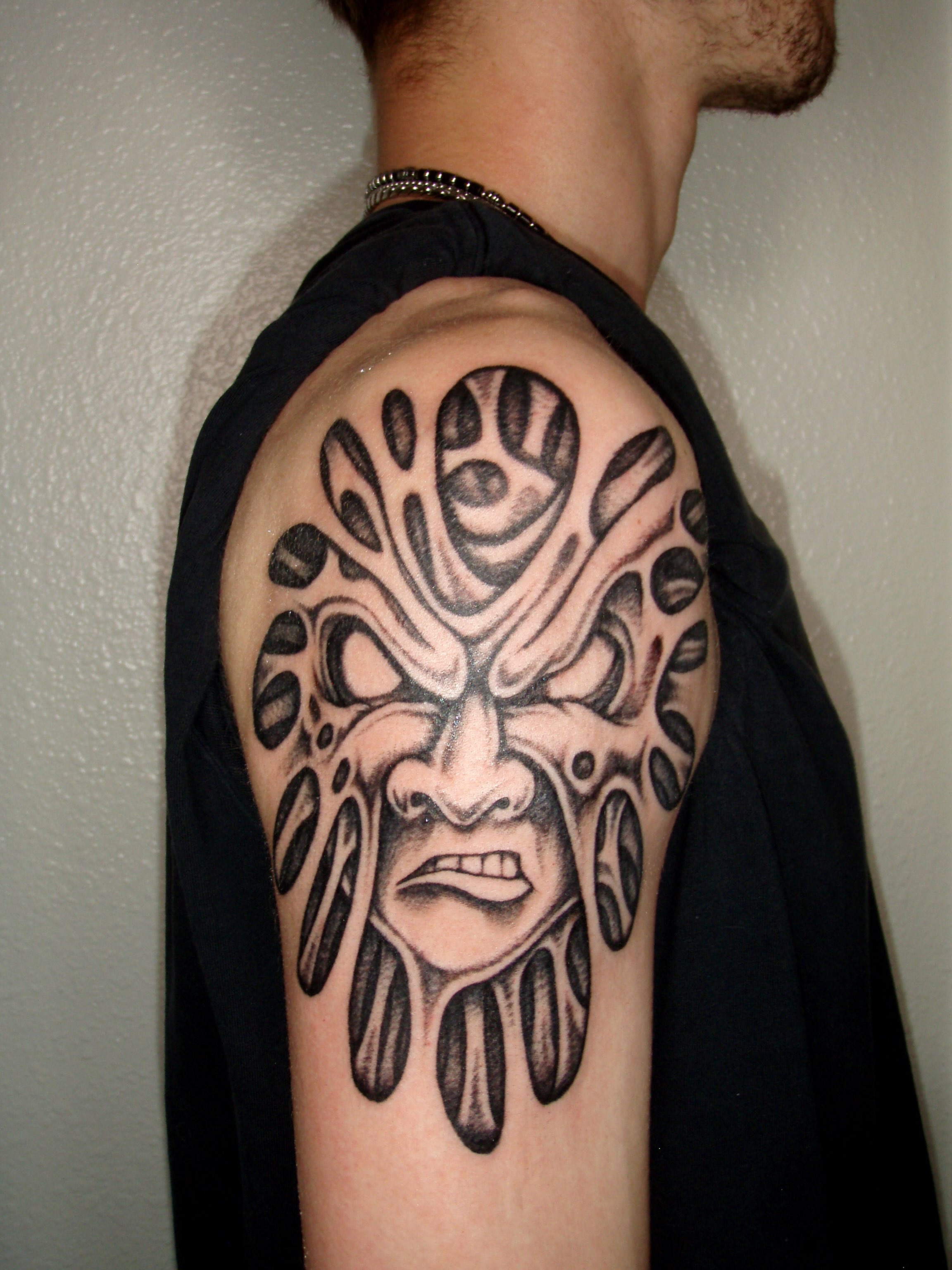 Mask geometric tattoo on the shoulder by Brendan Smith