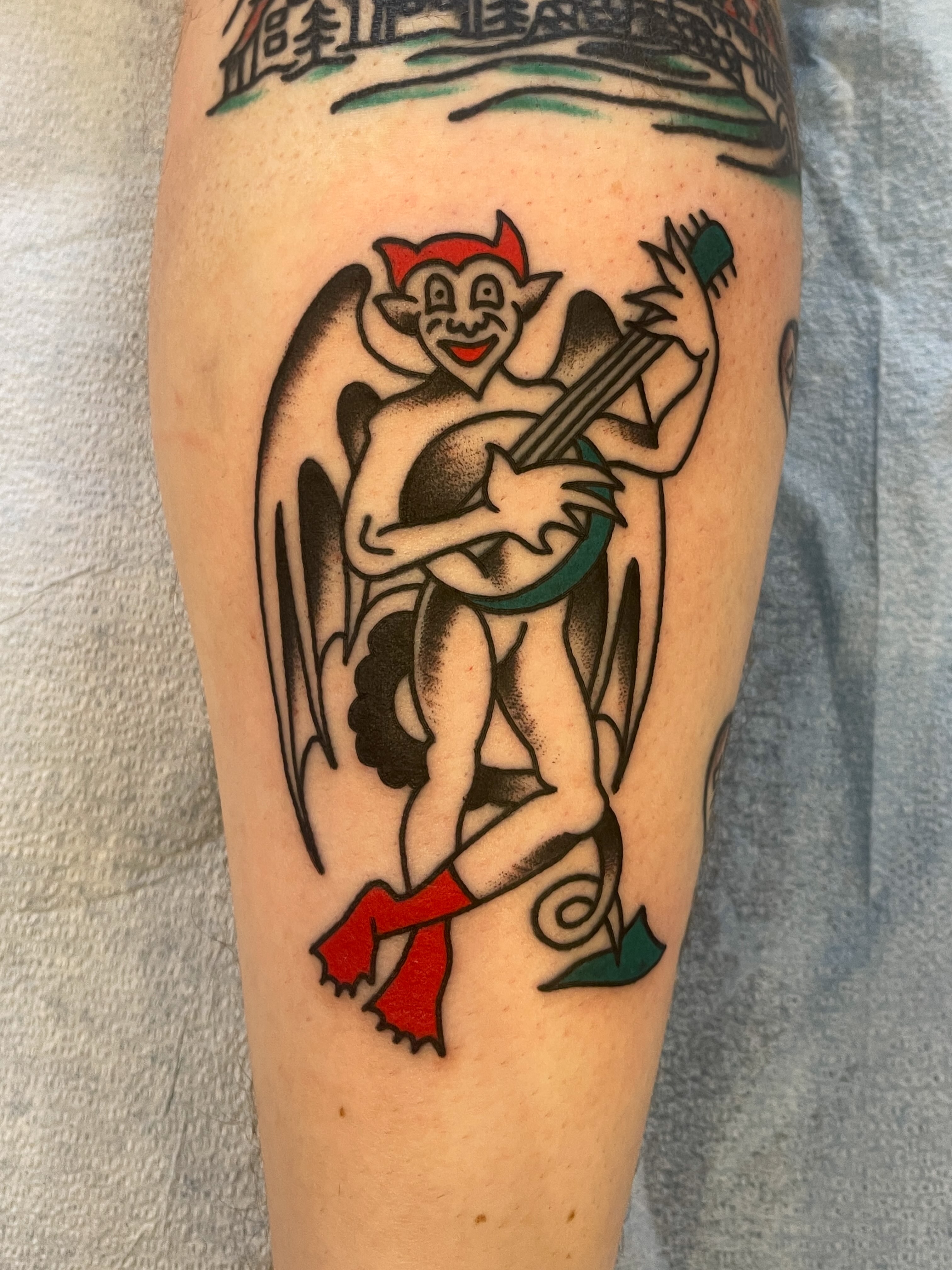 Devil playing banjo American traditional tattoo on the forearm by Spencer Reisbeck