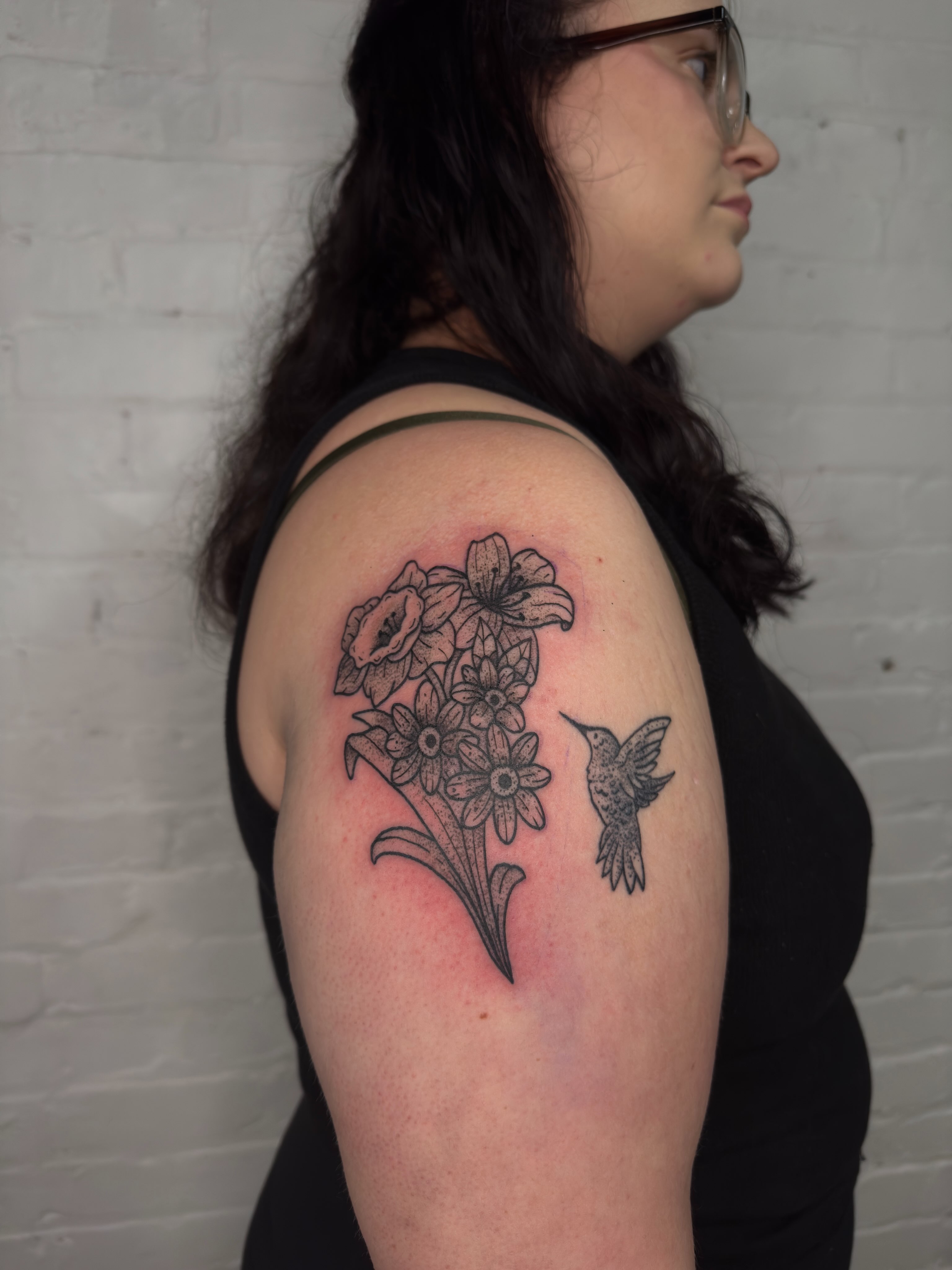 Flowers and hummingbird black and grey tattoo on the shoulder by Dennis Patterson