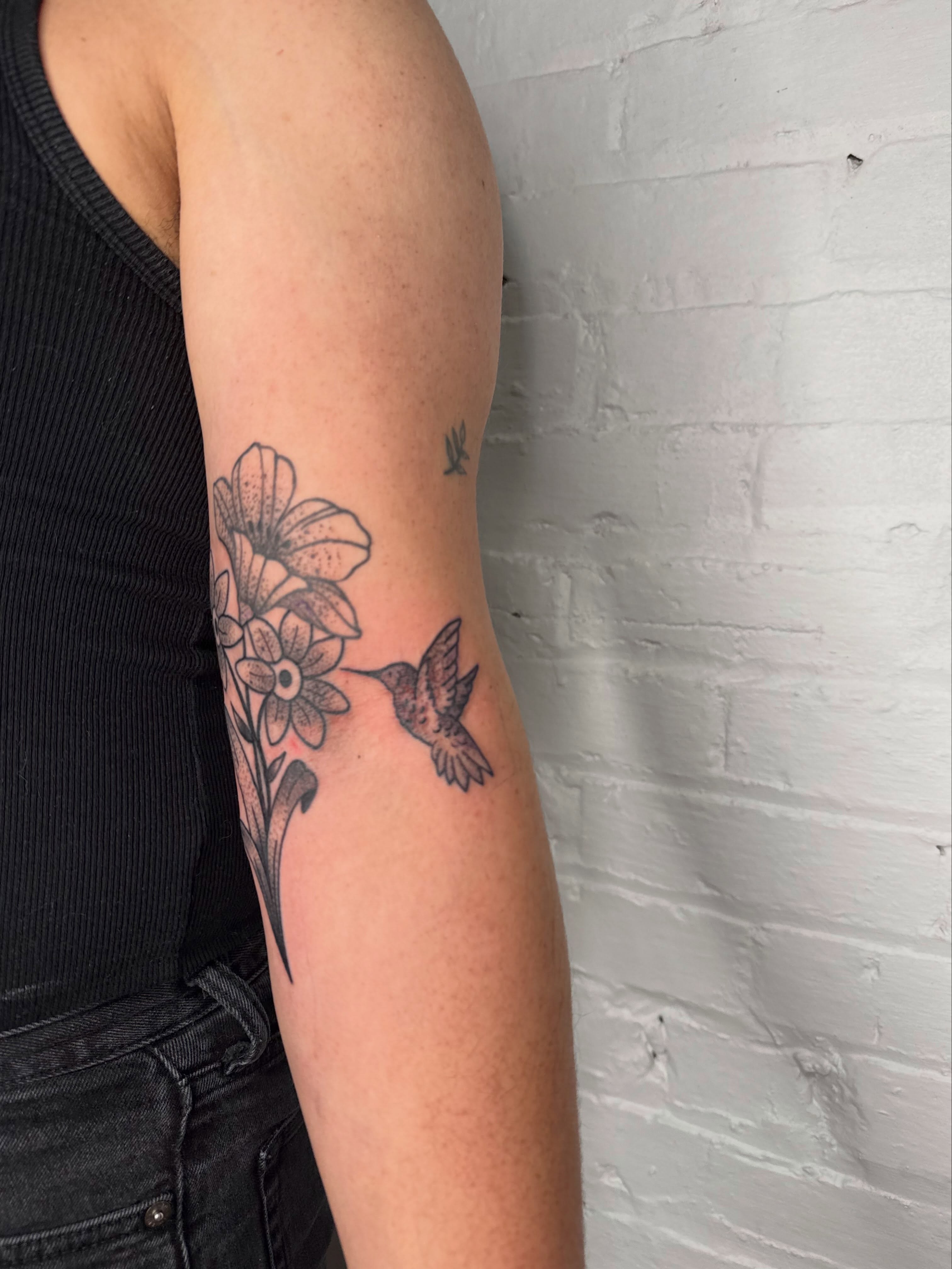 Hummingbird and flowers black and grey tattoo on the forearm by Dennis Patterson