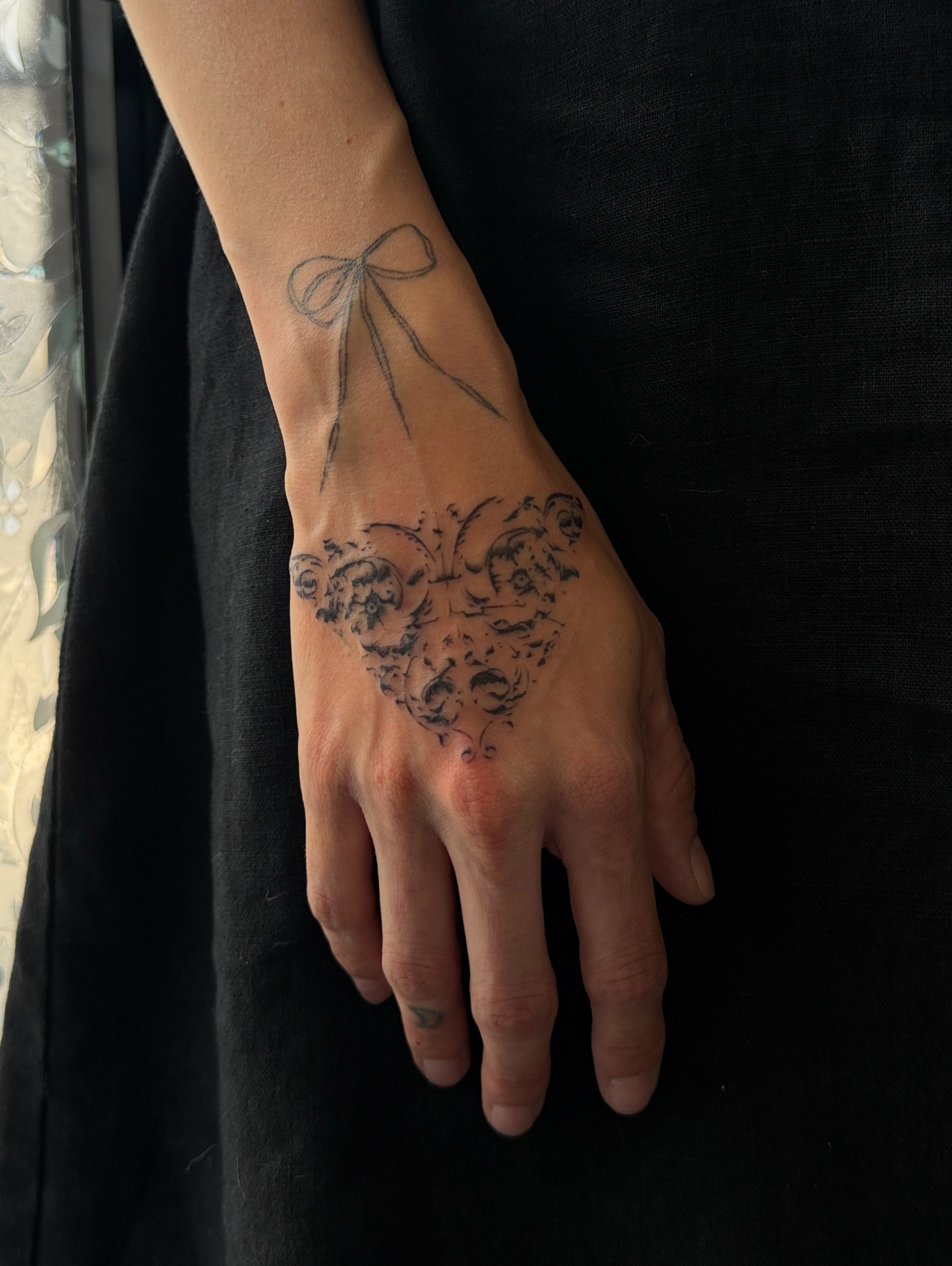 Bow and floral black and grey tattoo on the hand by gabrielle rosemary ποΈ