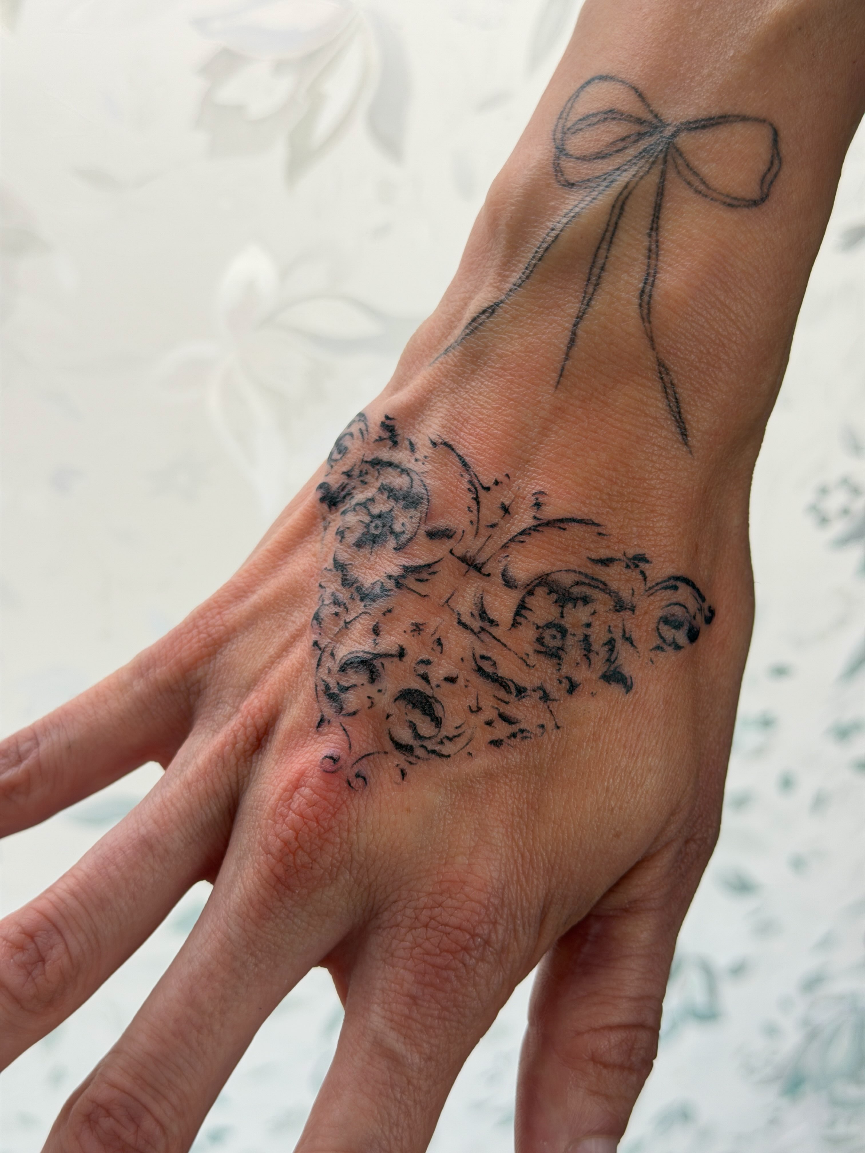 Bow and floral black and grey tattoo on the hand by gabrielle rosemary ποΈ