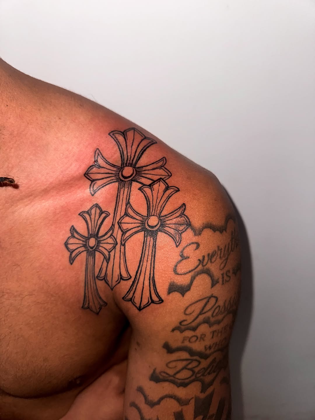 Three crosses and lettering tattoo on the shoulder by Comet