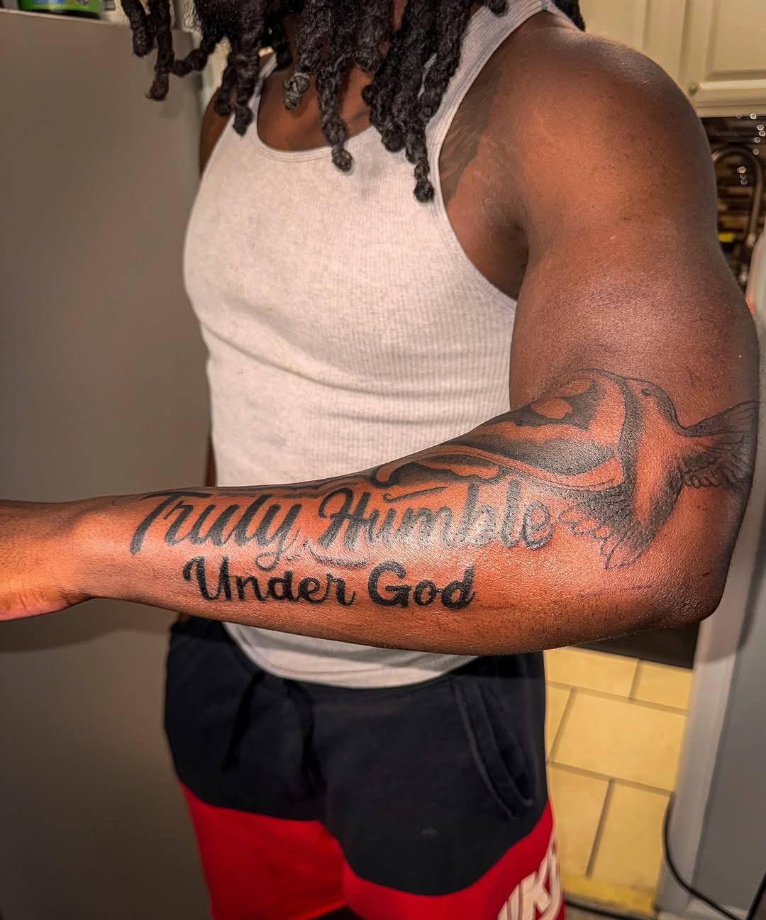 Truly Humble Under God with dove lettering tattoo on the forearm by Comet