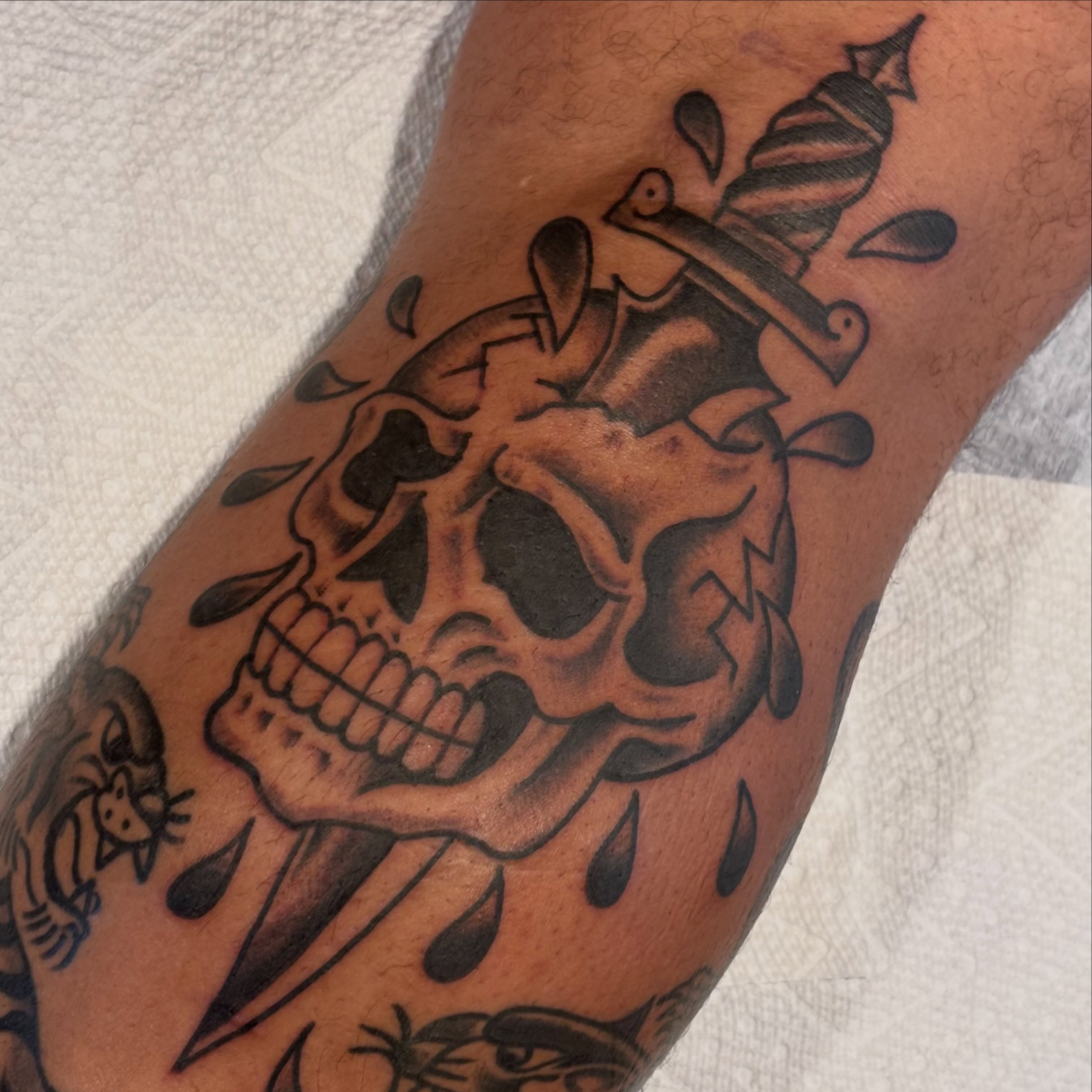 Skull with knife American traditional tattoo on the forearm by Malachi