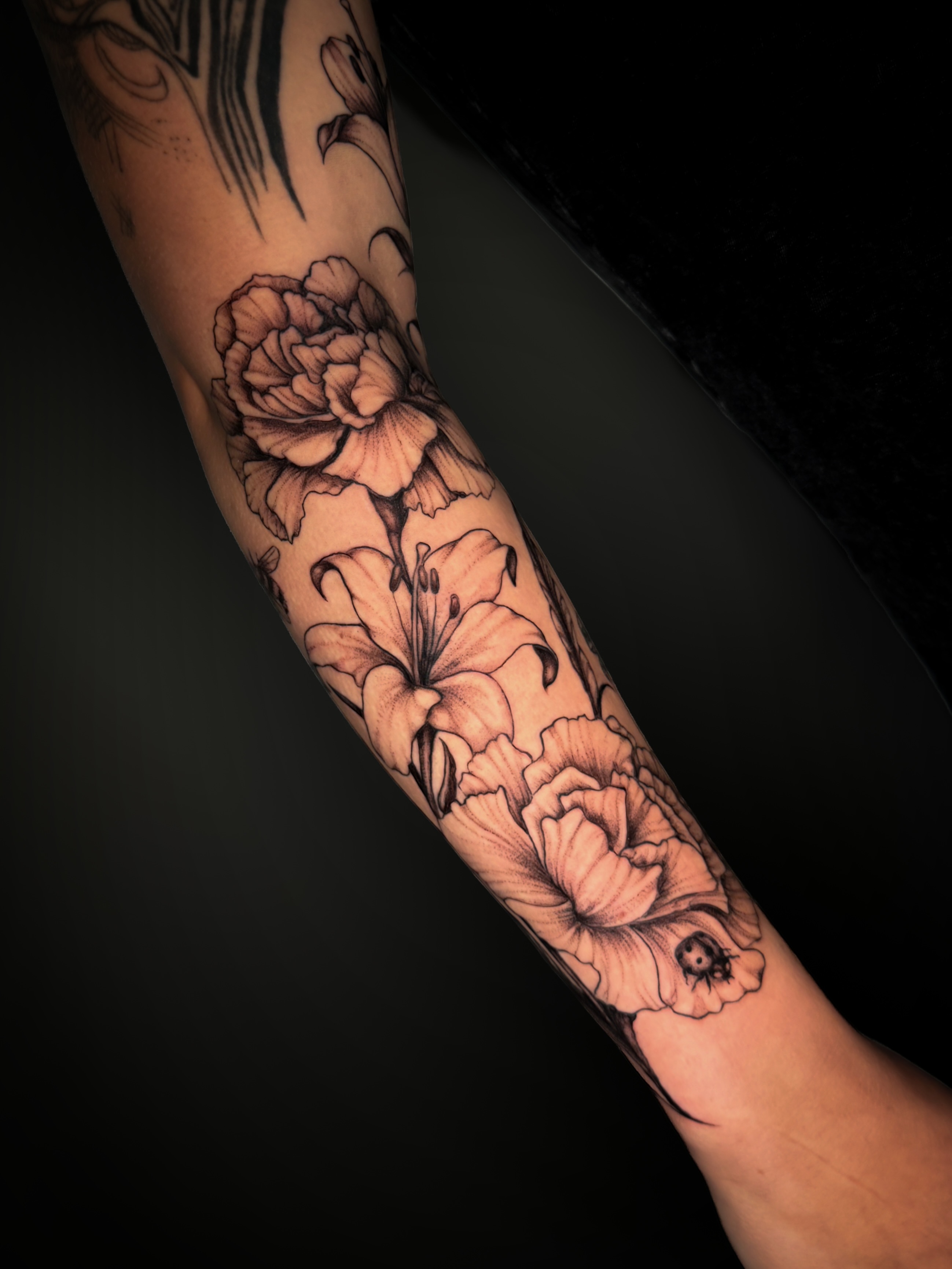 Flowers black and grey tattoo on the forearm by Kam Mills