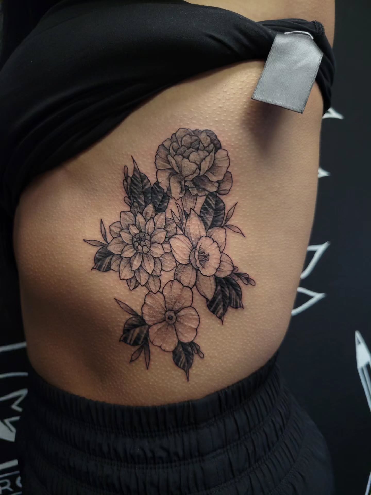 Floral bouquet black and grey tattoo on the ribs by Marina Cobb