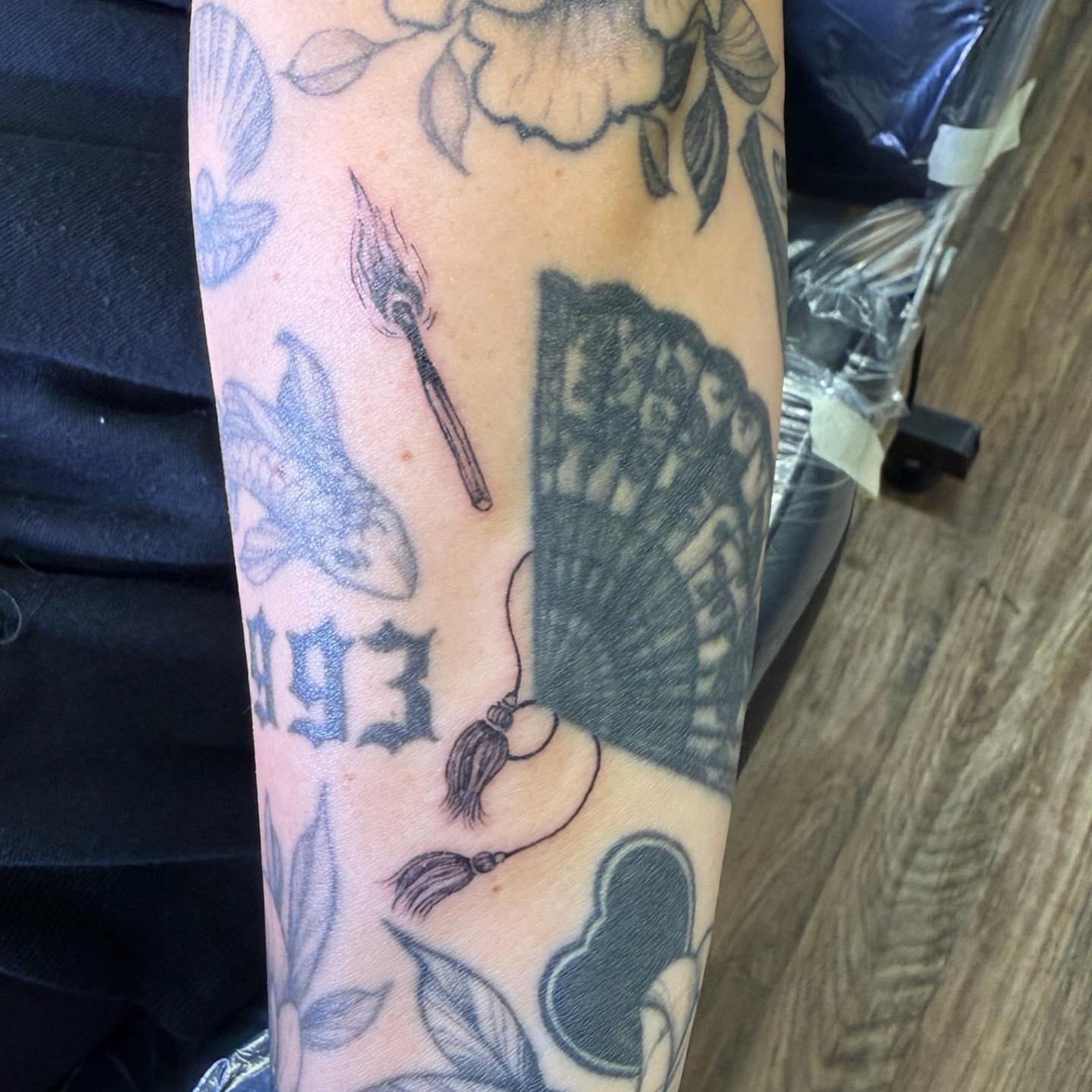 Tassel and fan black and grey tattoo on the forearm by PxINK, Crystal, Minnesota