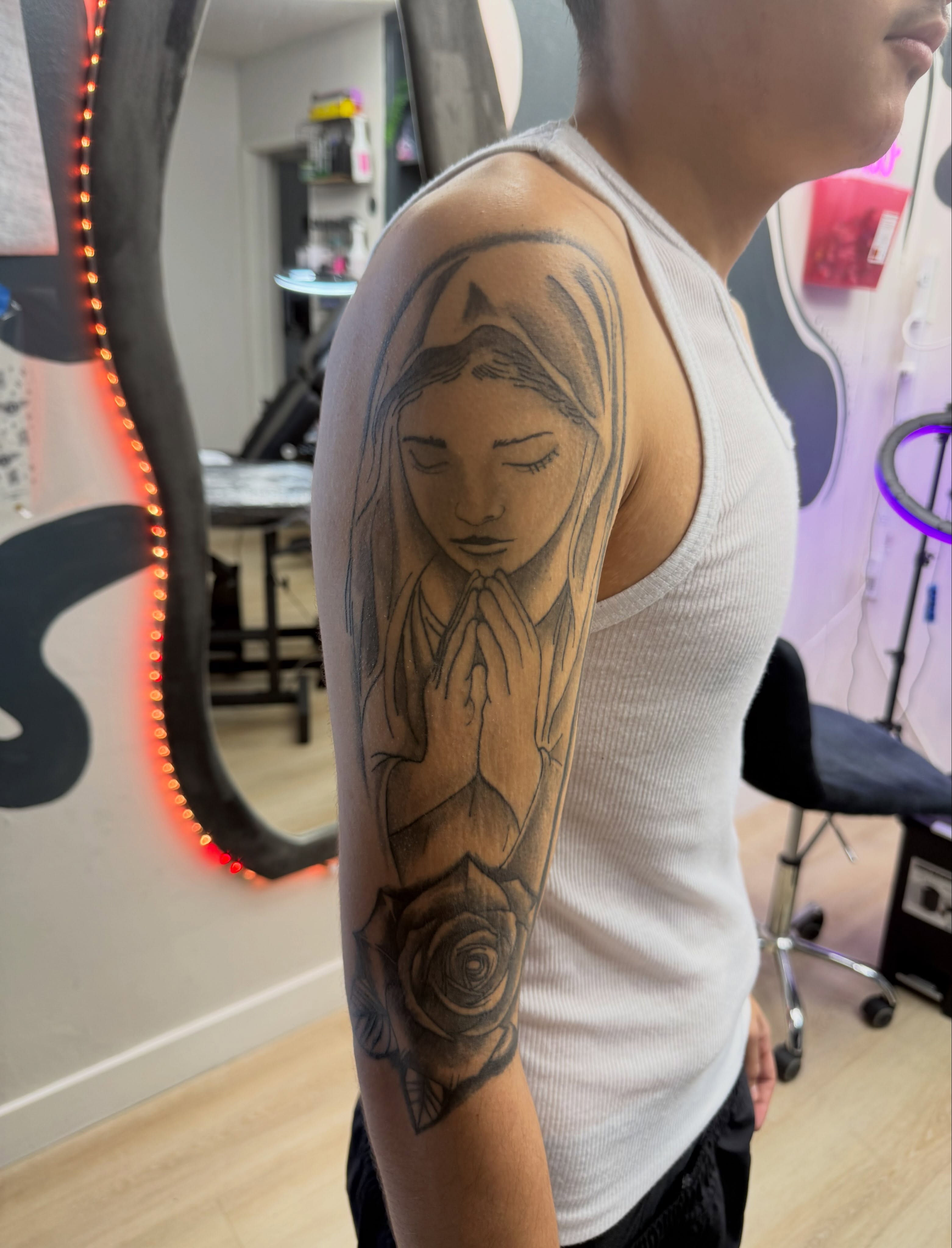 Praying girl black and grey tattoo on the upper arm by Kelsoink
