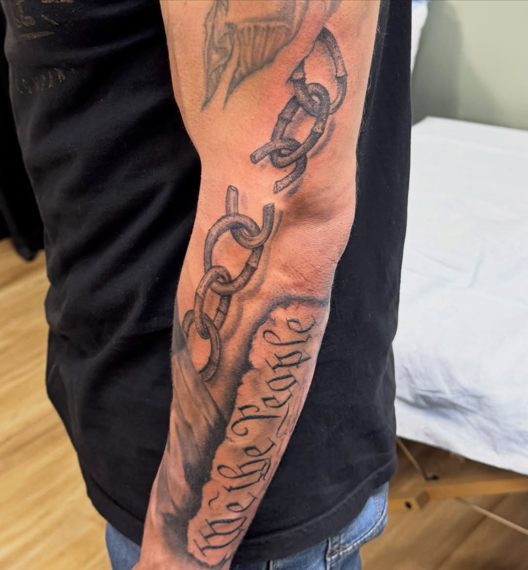 Chains and text black and grey tattoo on the forearm by Elmer Lethco